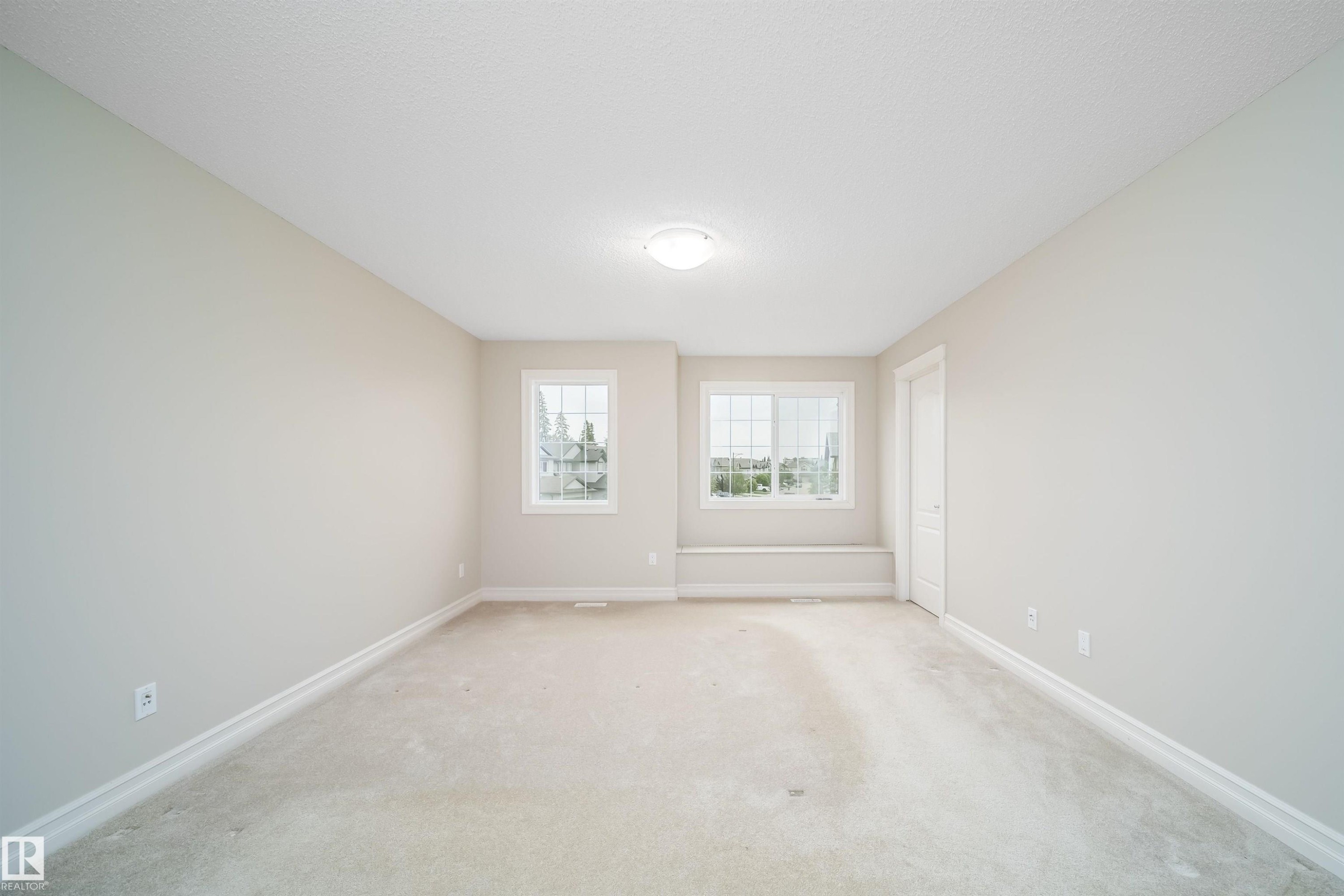 Neutral-toned room featuring a light-colored carpet, white trim, and a flush-mount ceiling light - 11312 13 Ave Sw, Edmonton, AB