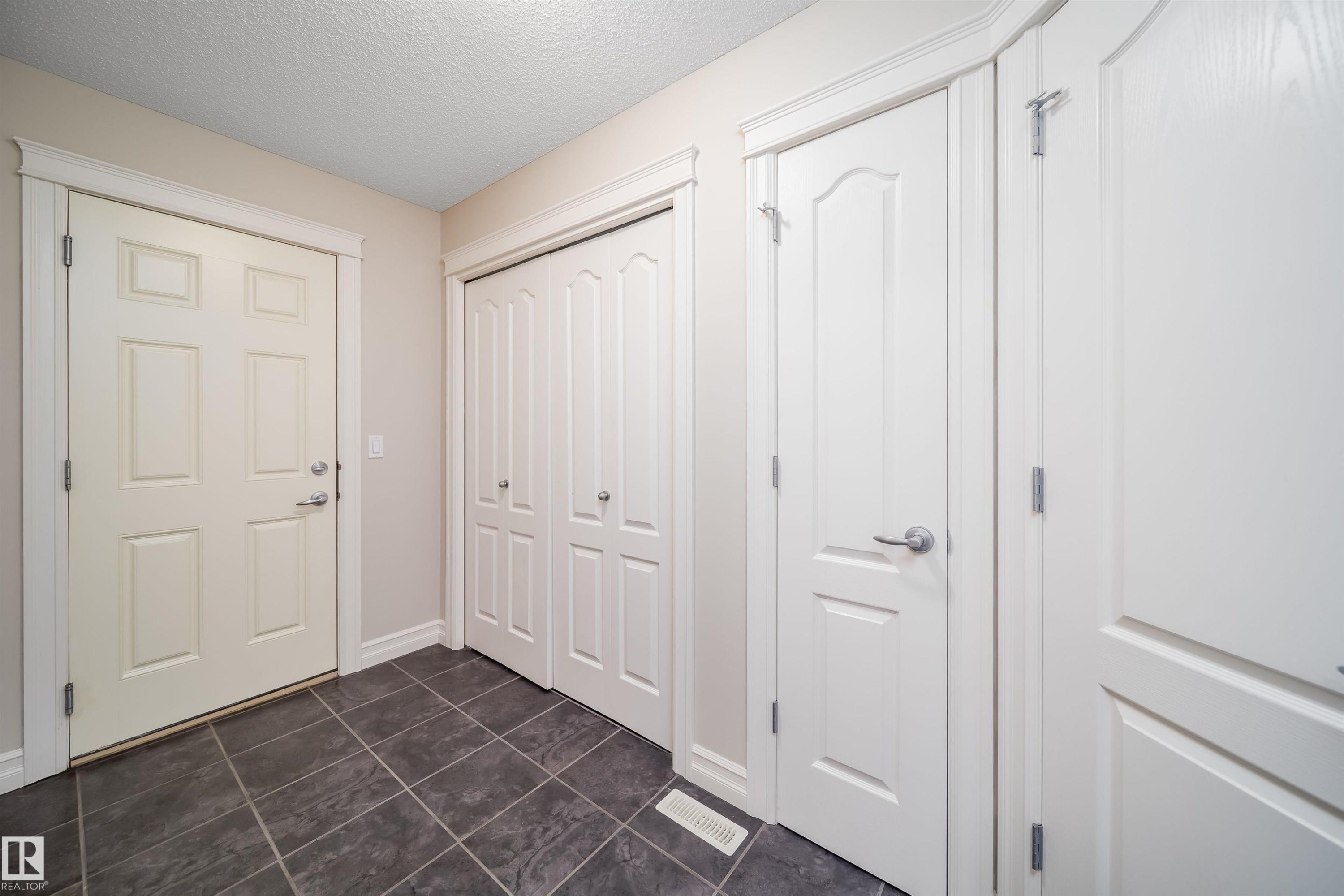 Entryway featuring dark rectangular floor tiles and light-toned walls - 11312 13 Ave Sw, Edmonton, AB