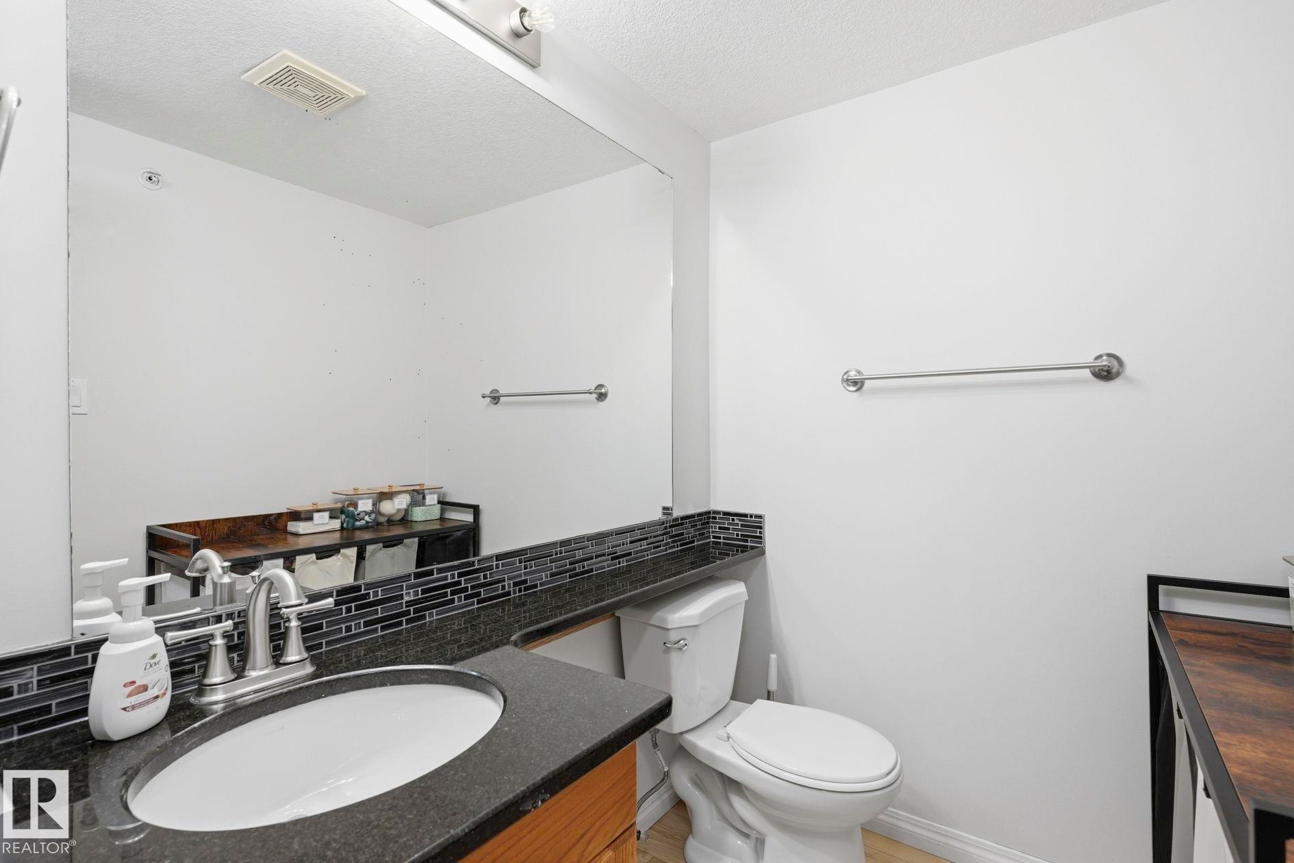Bathroom with a vanity featuring a dark countertop, an integrated sink, and a chrome faucet - #426 3425 19 St Nw, Edmonton, AB