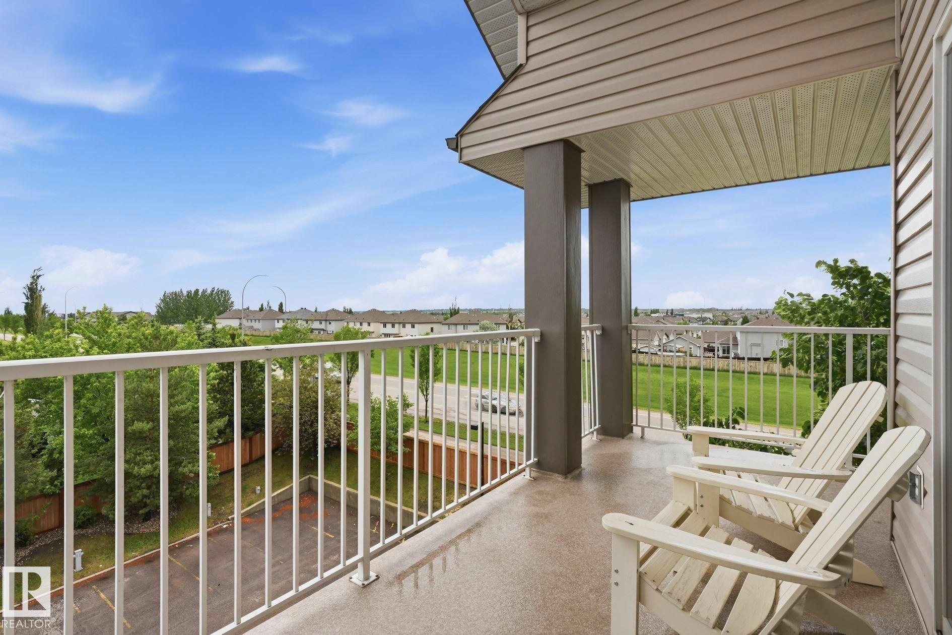 Covered balcony with a concrete surface and white metal railing - #426 3425 19 St Nw, Edmonton, AB