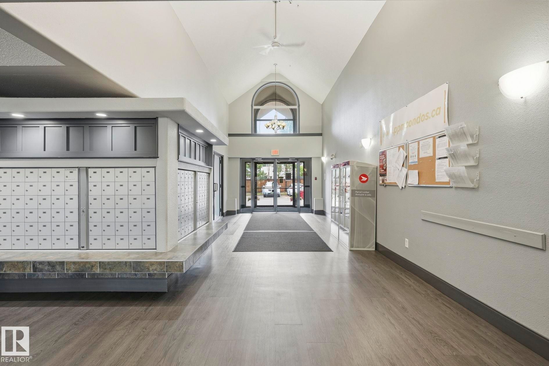 Spacious entry lobby featuring vaulted ceilings, wood-finish flooring, recessed lighting, and ample mailbox facilities - #426 3425 19 St Nw, Edmonton, AB