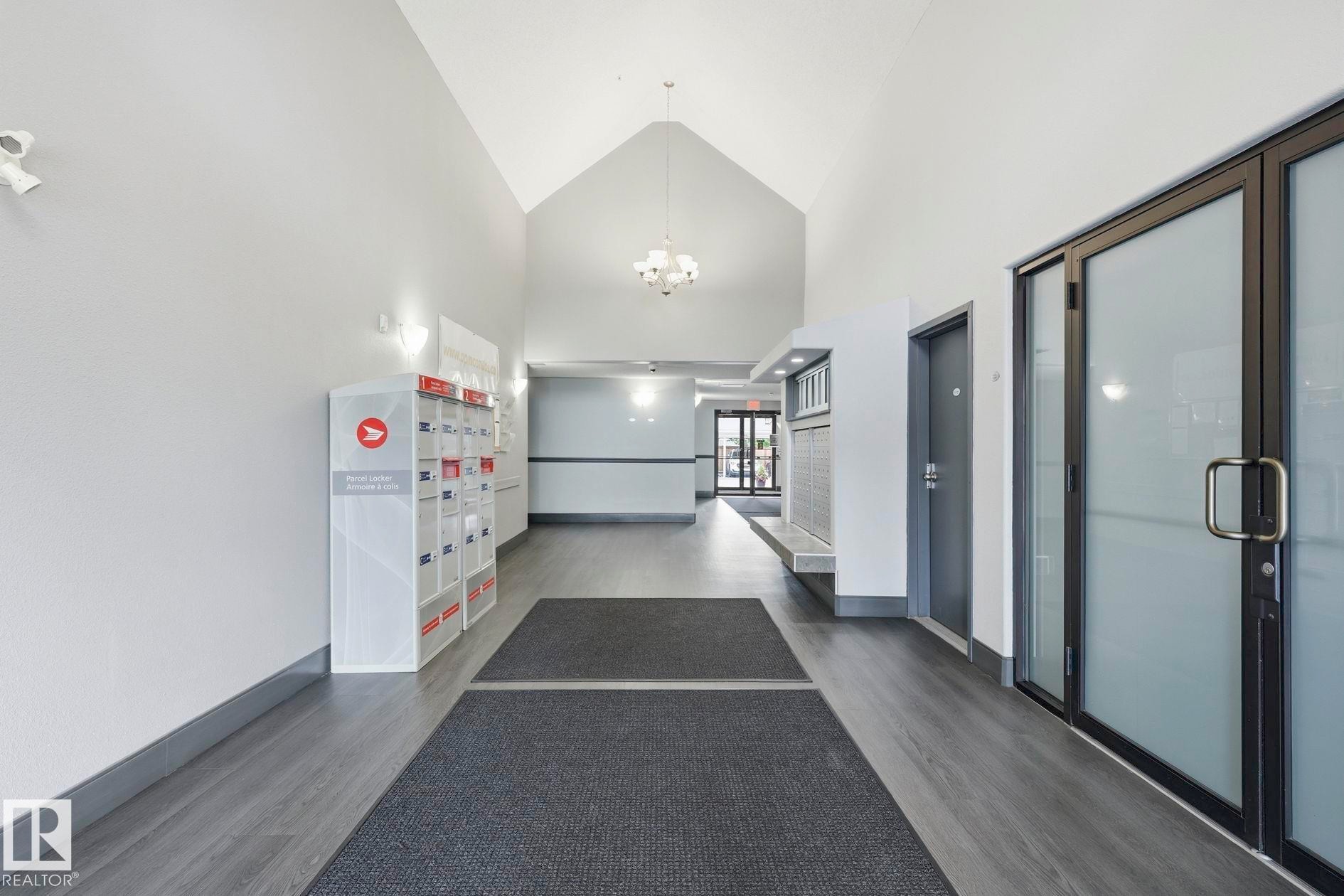 Vaulted ceiling entrance featuring wood-finish flooring, recessed lighting, and mailboxes - #426 3425 19 St Nw, Edmonton, AB