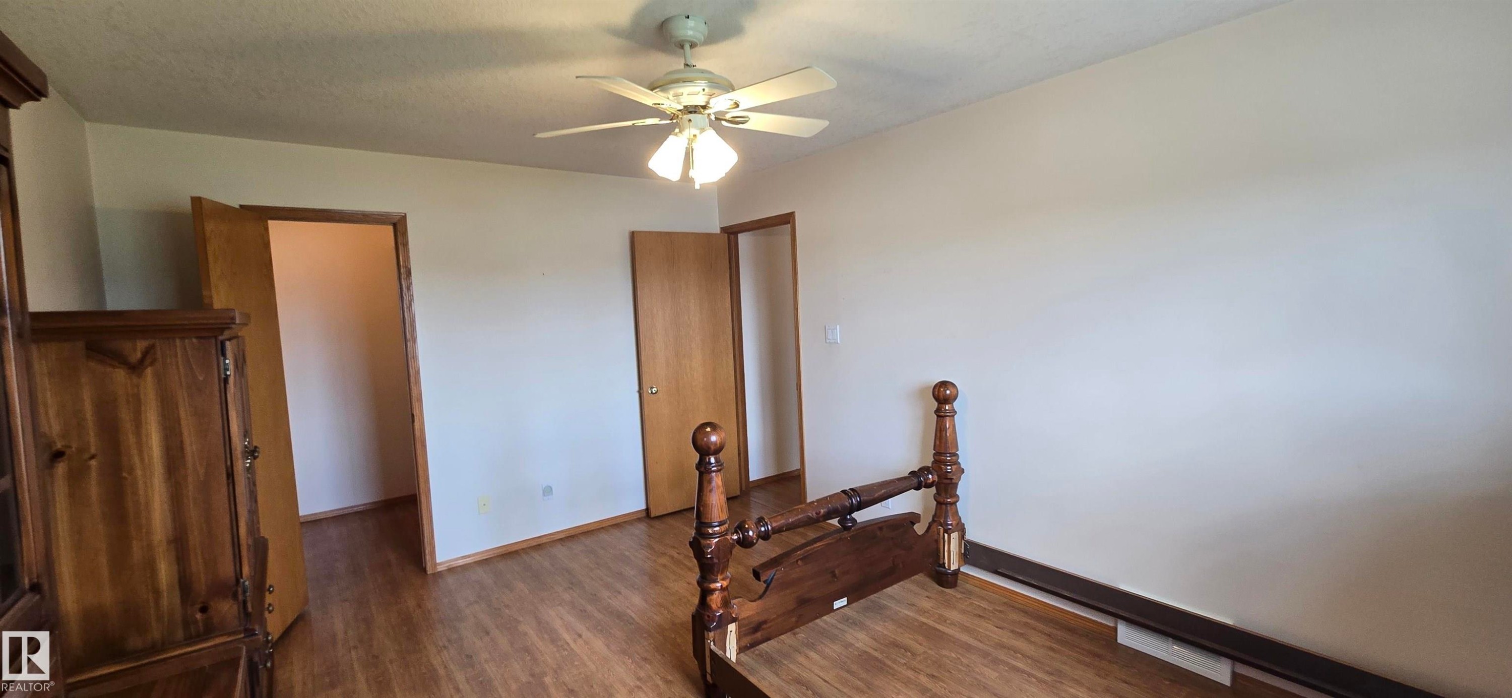 Spacious room featuring wood-finish flooring and a ceiling fan with integrated lighting - 4519 59 Ave, Vegreville, AB