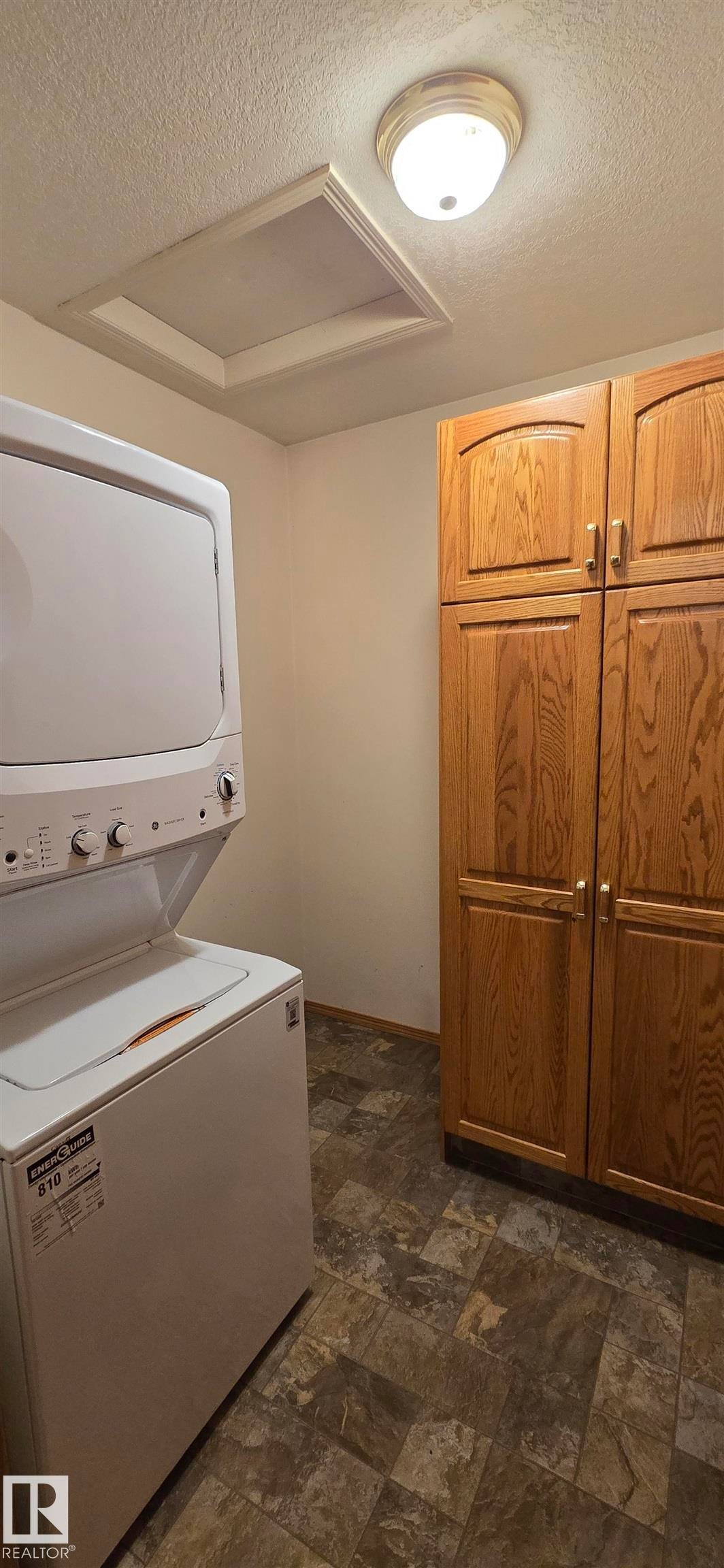 Dedicated utility area featuring wood-finish cabinetry and patterned flooring - 4519 59 Ave, Vegreville, AB
