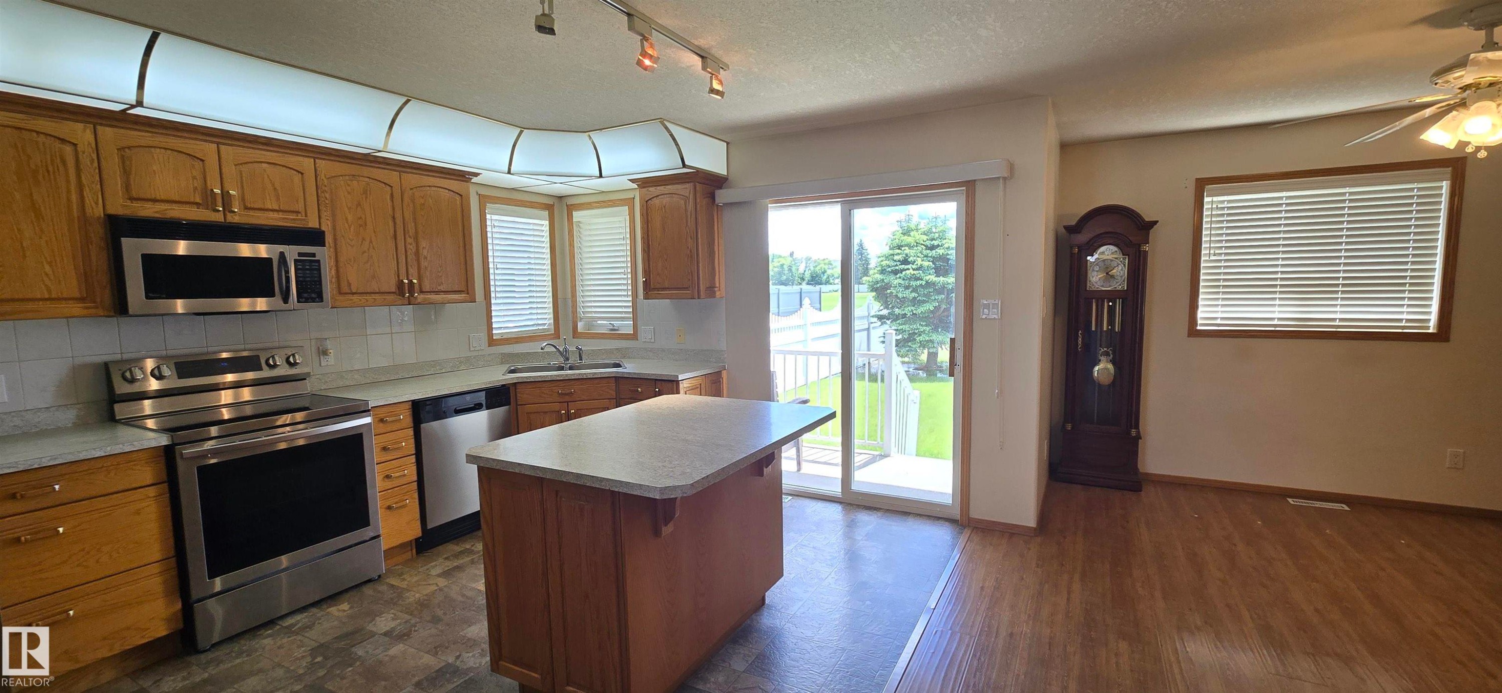 Kitchen with wood cabinetry, stainless steel appliances, and a central island - 4519 59 Ave, Vegreville, AB
