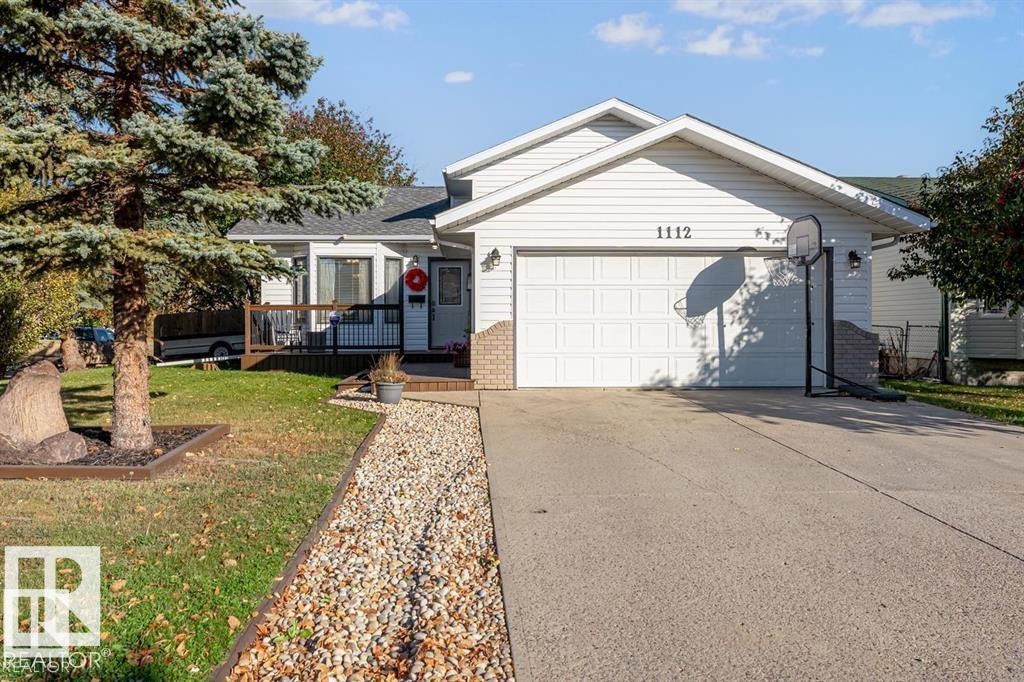 White siding exterior with a single-car garage, concrete driveway, and a front deck - 1112 13 Avenue, Cold Lake, AB - Outdoor With Deck Patio Veranda