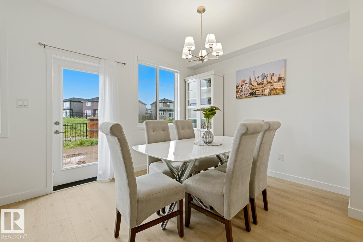 Bright dining area featuring light wood-finish flooring, white walls, and a contemporary chandelier - 22924 82 Ave Nw, Edmonton, AB - Indoor Photo Showing Dining Room