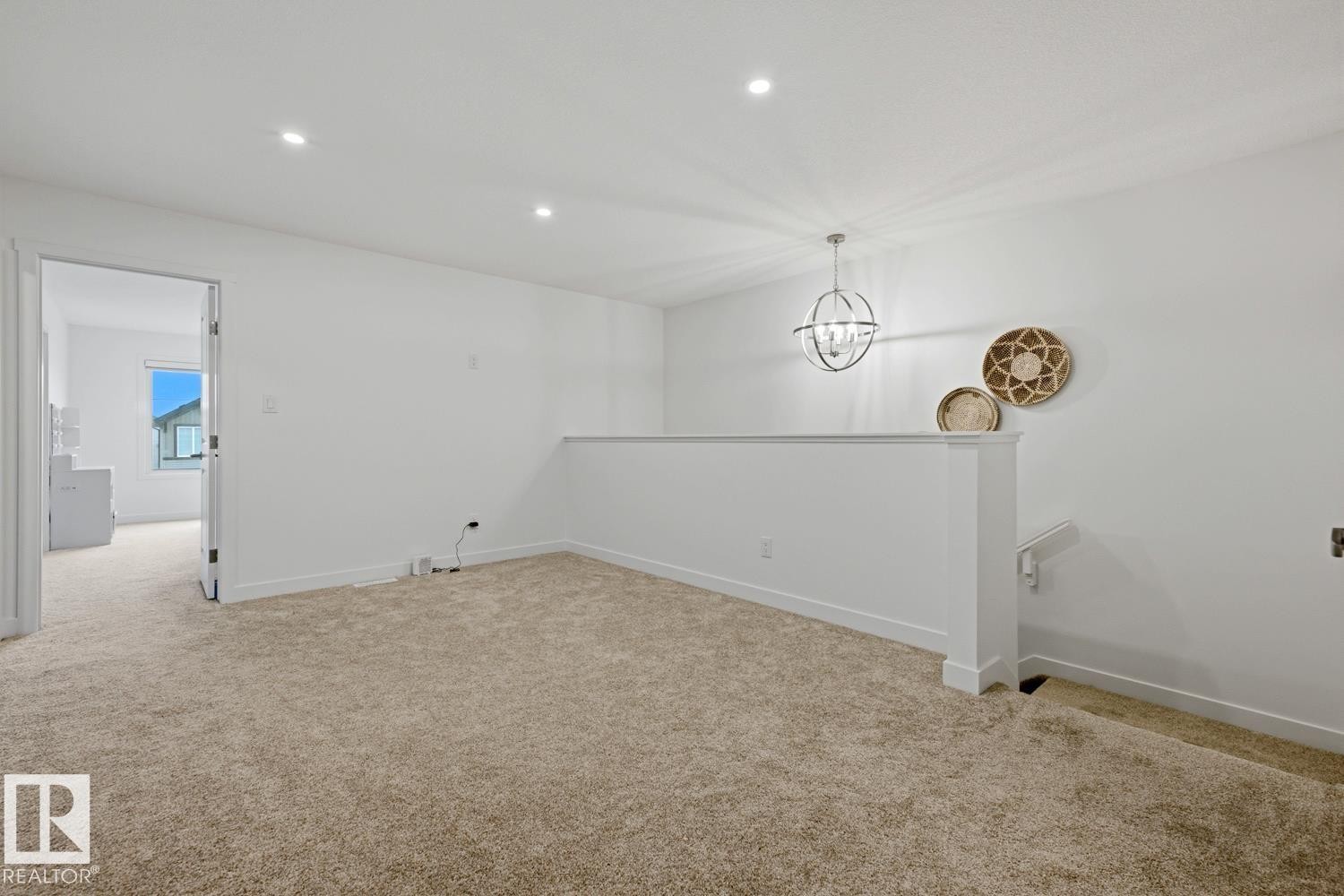 Carpeted loft area featuring a modern orb chandelier, recessed lighting, white half-wall railing, and a doorway to an additional room - 22924 82 Ave Nw, Edmonton, AB - Indoor Photo Showing Other Room