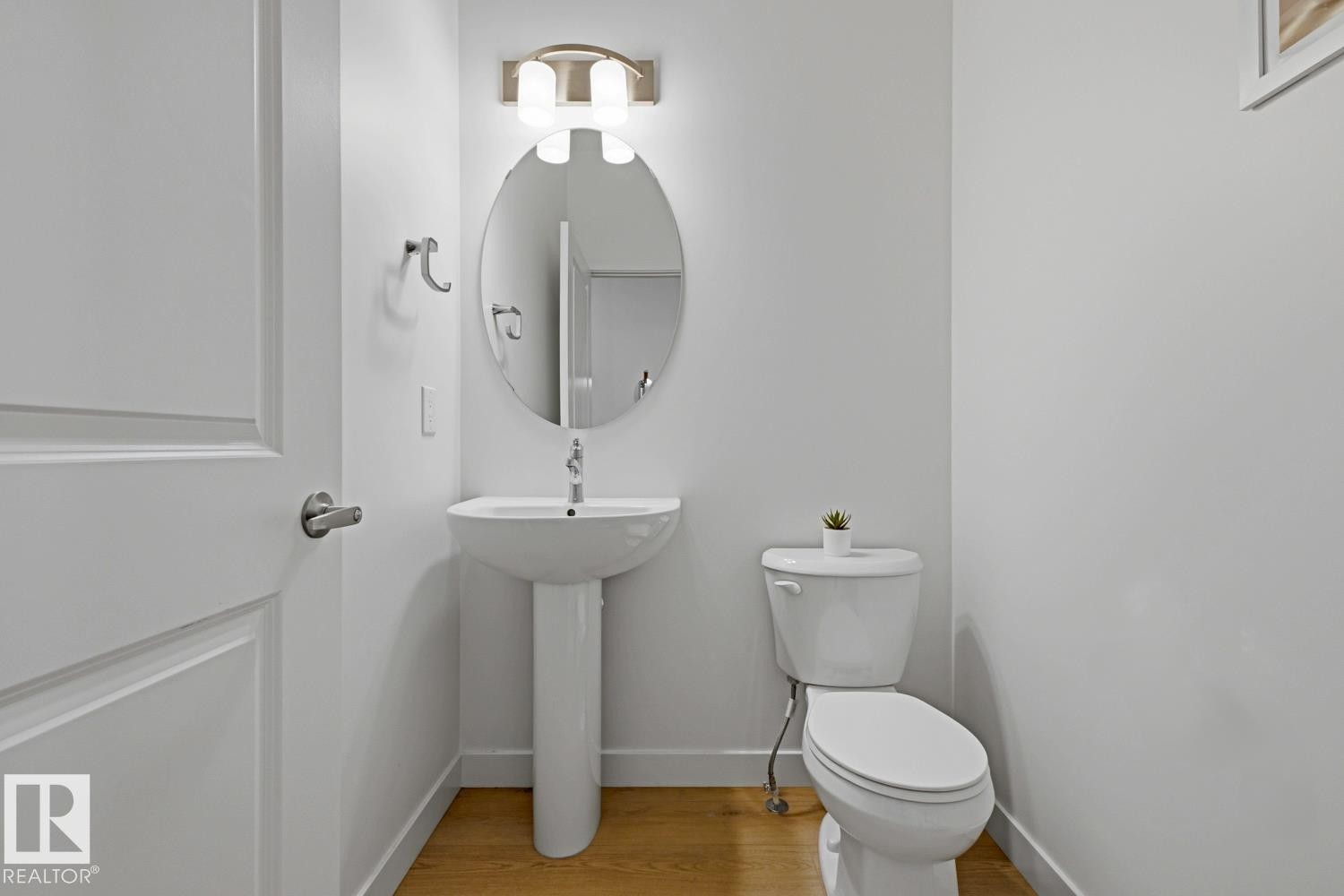 Pedestal sink with an oval mirror and contemporary vanity lighting - 22924 82 Ave Nw, Edmonton, AB - Indoor Photo Showing Bathroom