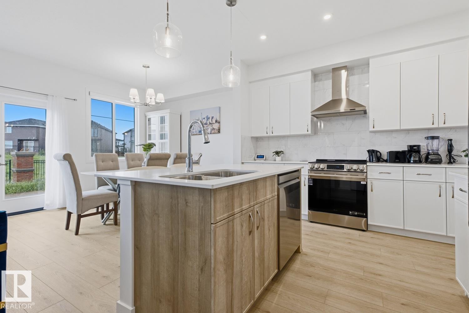 Modern kitchen featuring light wood-finish flooring, white cabinetry, and a large center island with an undermount sink - 22924 82 Ave Nw, Edmonton, AB - Indoor Photo Showing Kitchen With Double Sink With Upgraded Kitchen