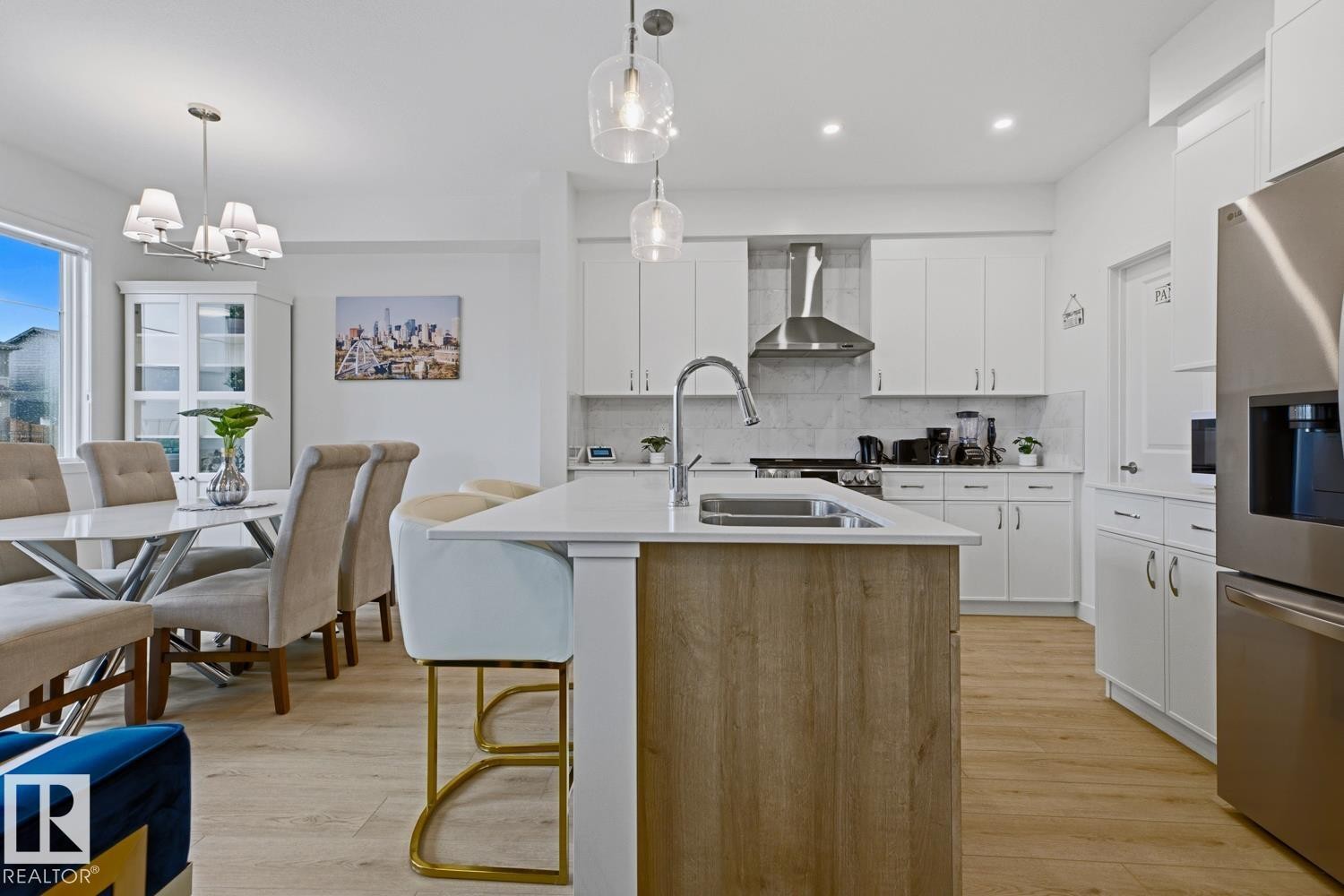 Modern kitchen featuring a large central island with wood-finish paneling, an undermount sink, and a chrome faucet - 22924 82 Ave Nw, Edmonton, AB - Indoor
