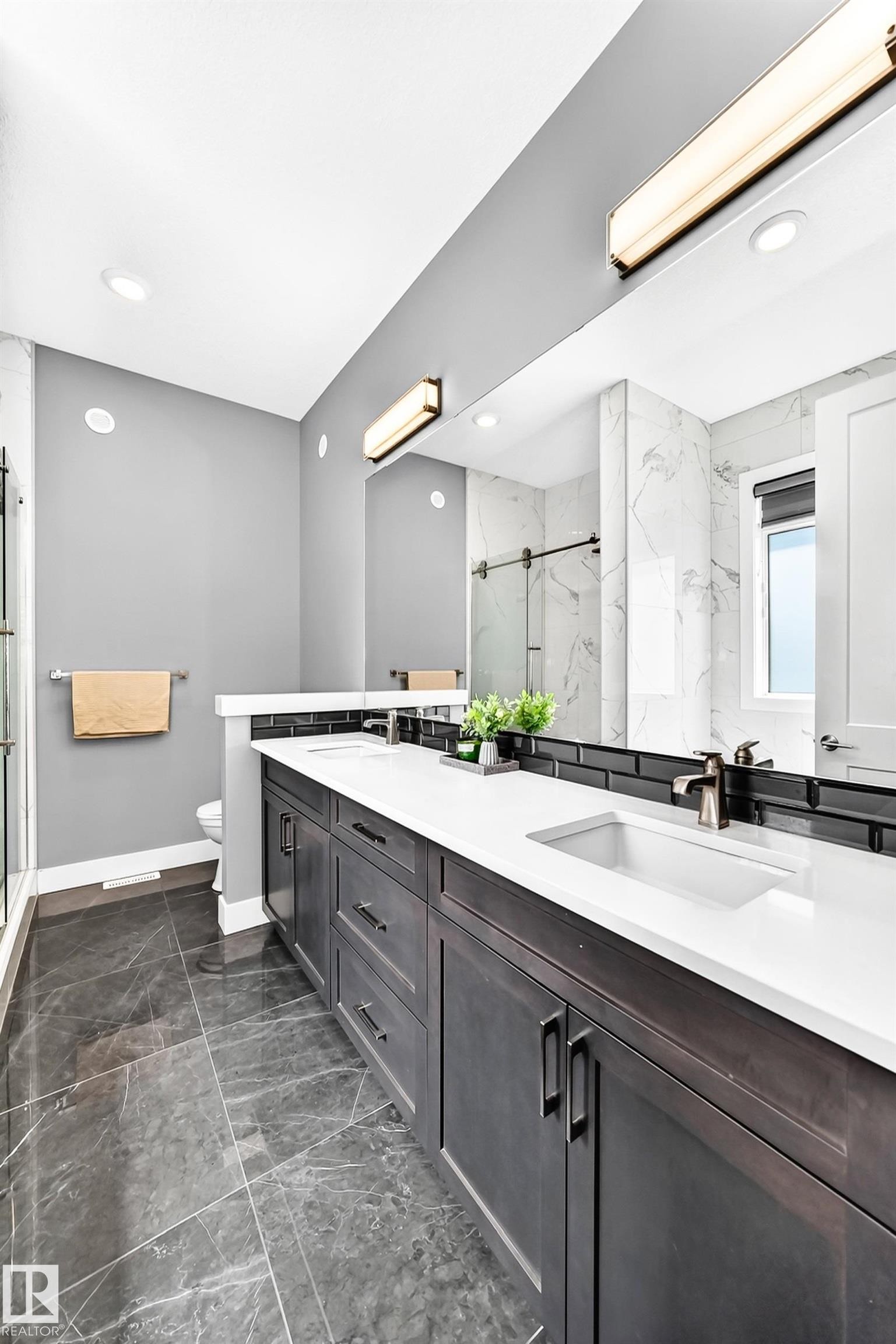 Double vanity with white countertops, dark wood-finish cabinetry, and contemporary bronze fixtures - 1781 Melrose Crescent, Edmonton, AB