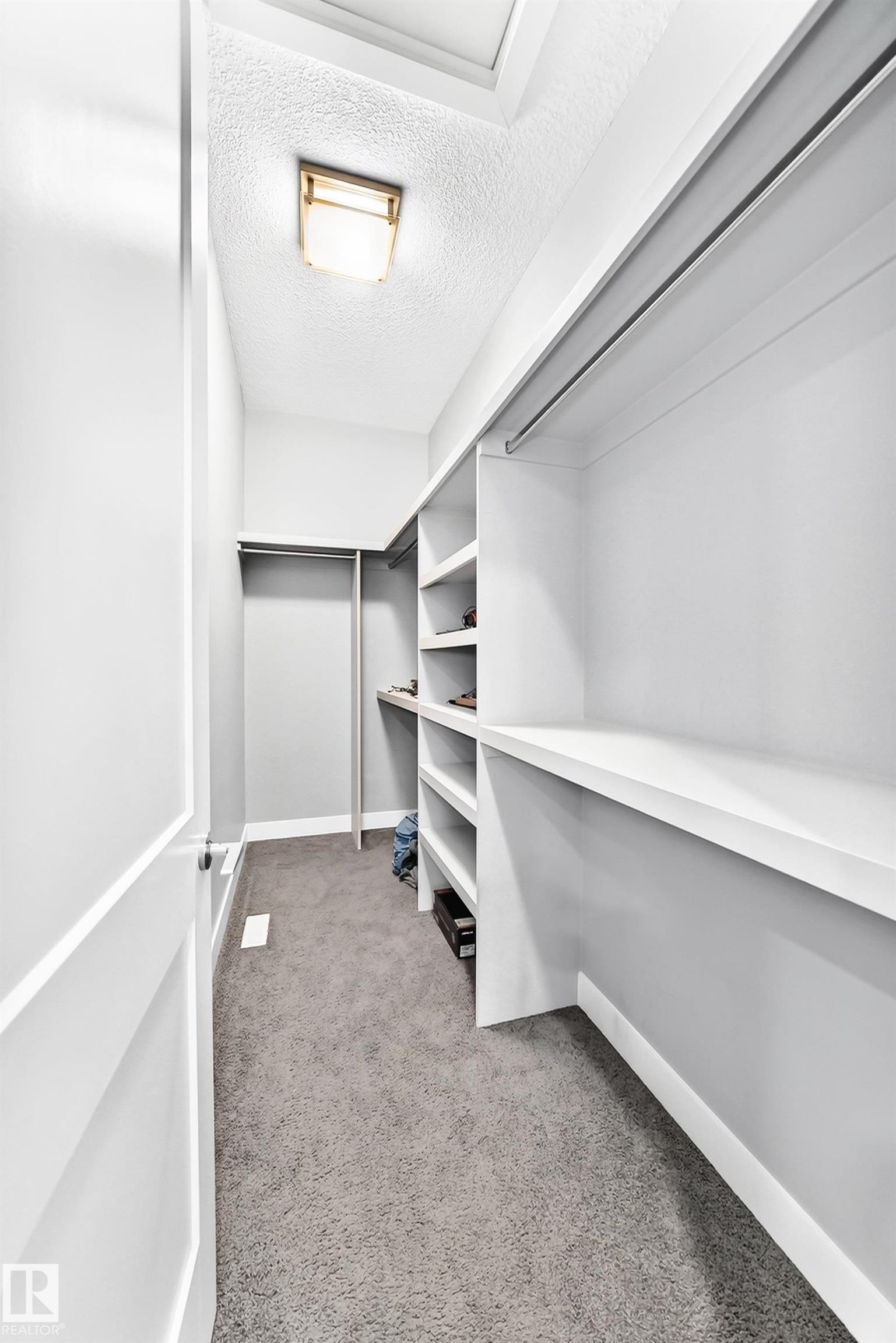 Walk-in closet featuring built-in shelving, hanging rods, recessed ceiling light, and a skylight - 1781 Melrose Crescent, Edmonton, AB