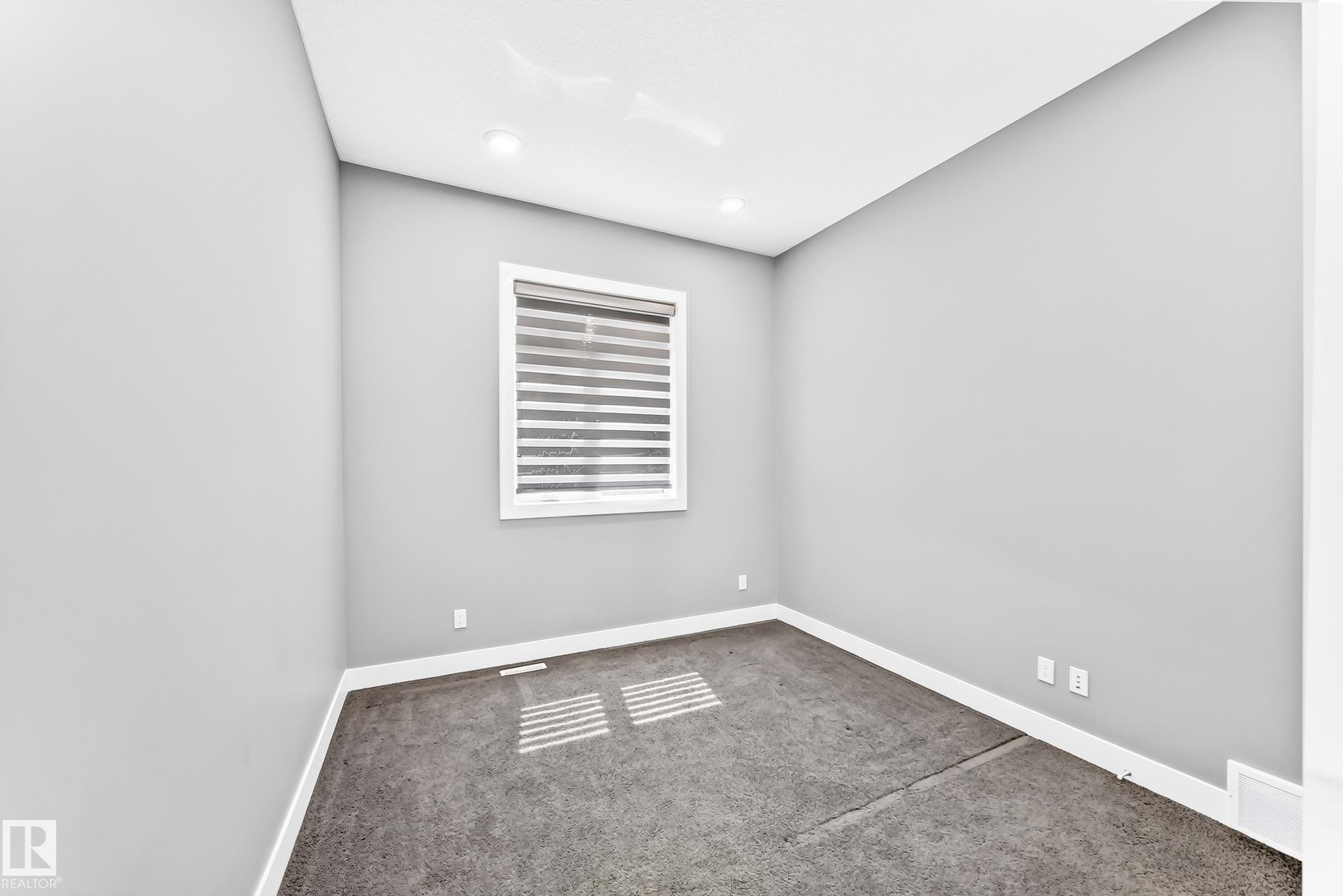Room featuring light gray walls, white trim, and dark gray carpeting - 1781 Melrose Crescent, Edmonton, AB
