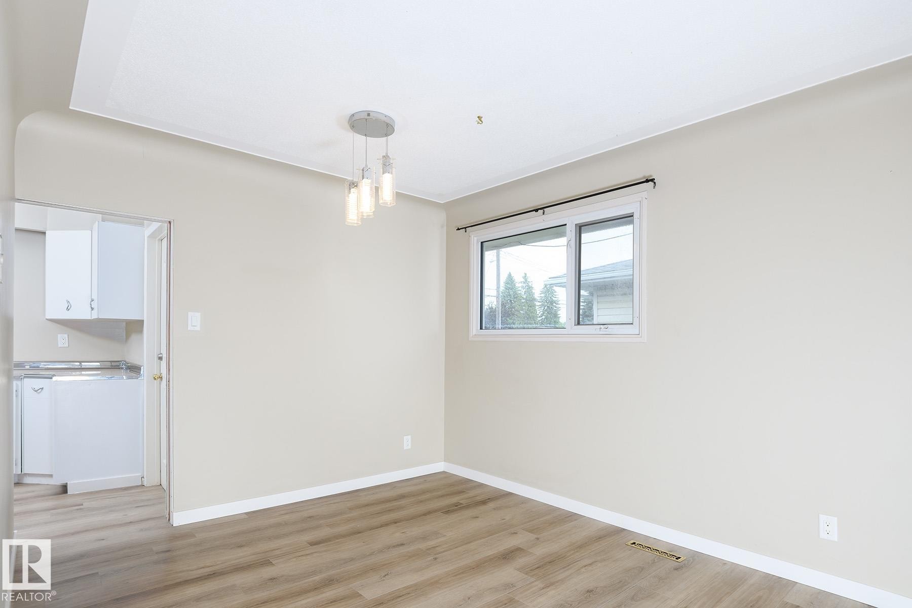 Interior room with wood-finish flooring, light neutral wall paint, and white trim - 9607 75 Street, Edmonton, AB