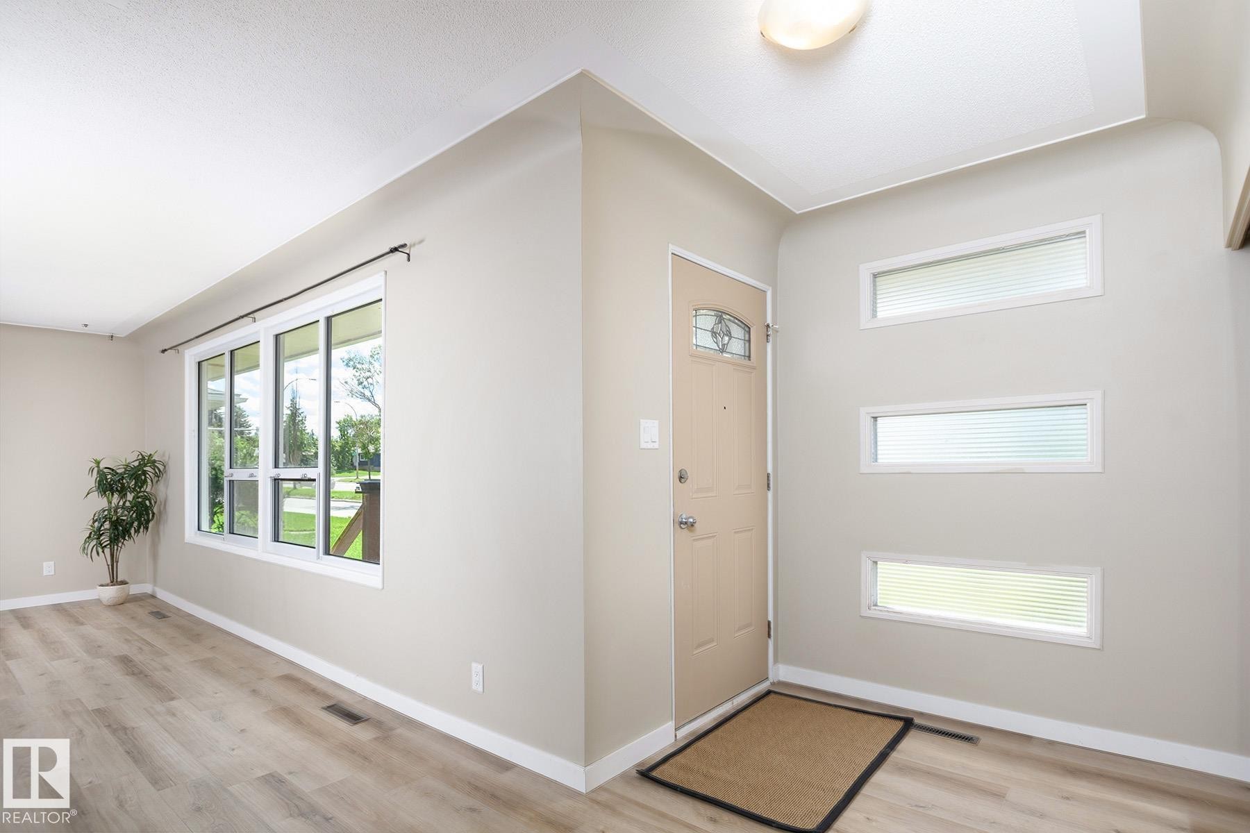 Front entry featuring a light-colored door with decorative glass, three horizontal windows, and a flush mount ceiling light - 9607 75 Street, Edmonton, AB