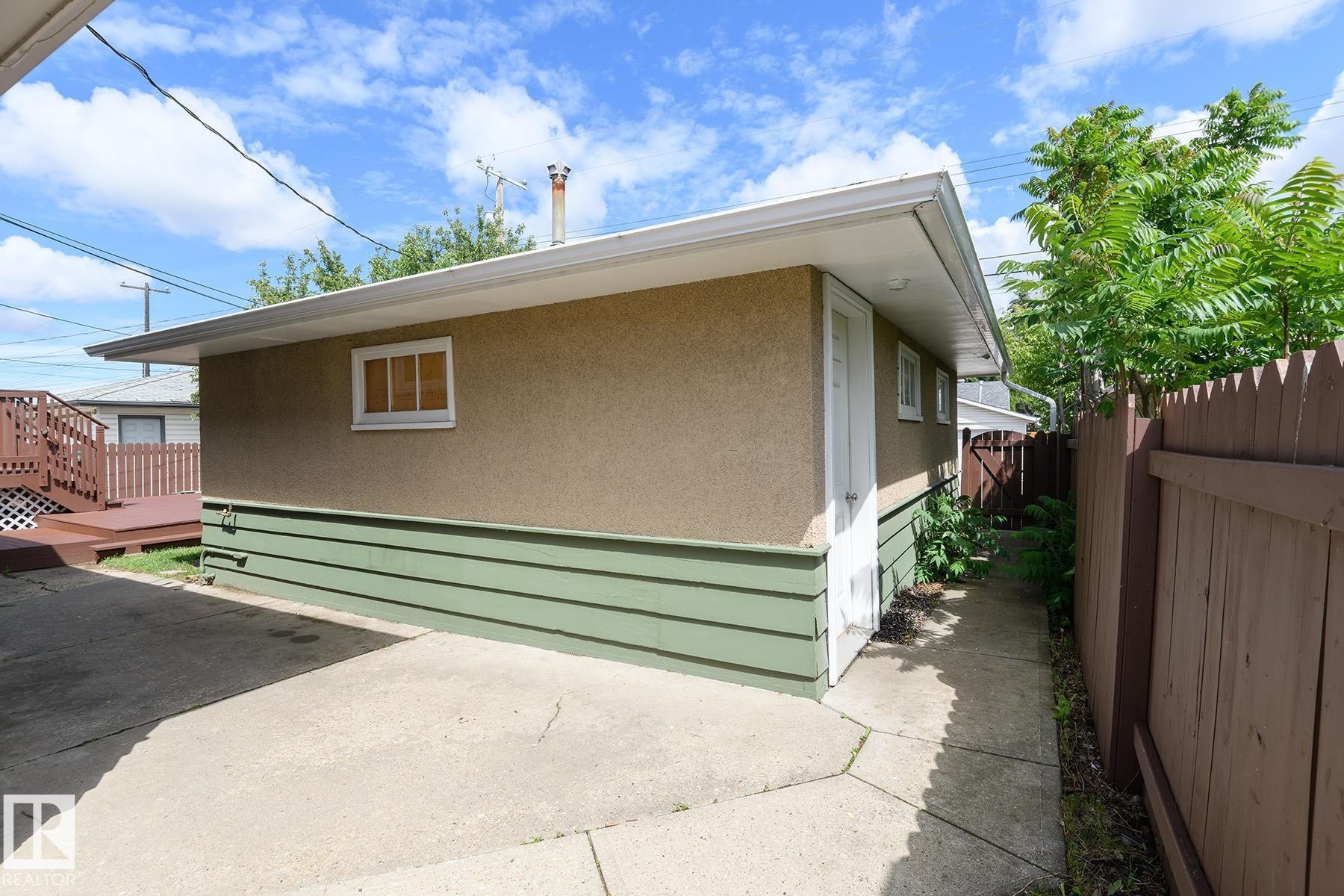 Exterior structure featuring stucco siding, green skirting, and white trim - 9607 75 Street, Edmonton, AB
