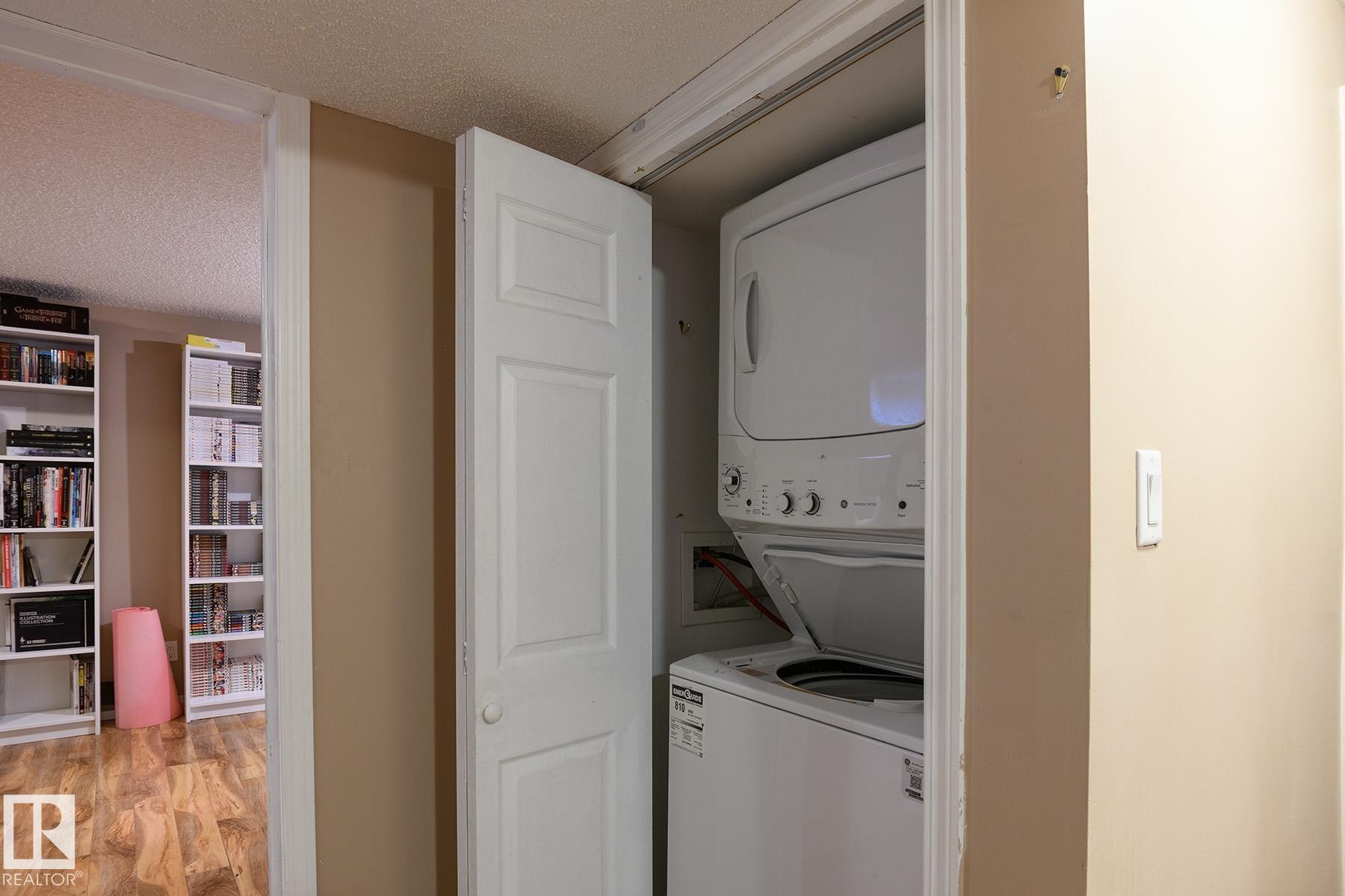 Laundry closet featuring a stacked white washer and dryer unit - 9607 75 Street, Edmonton, AB