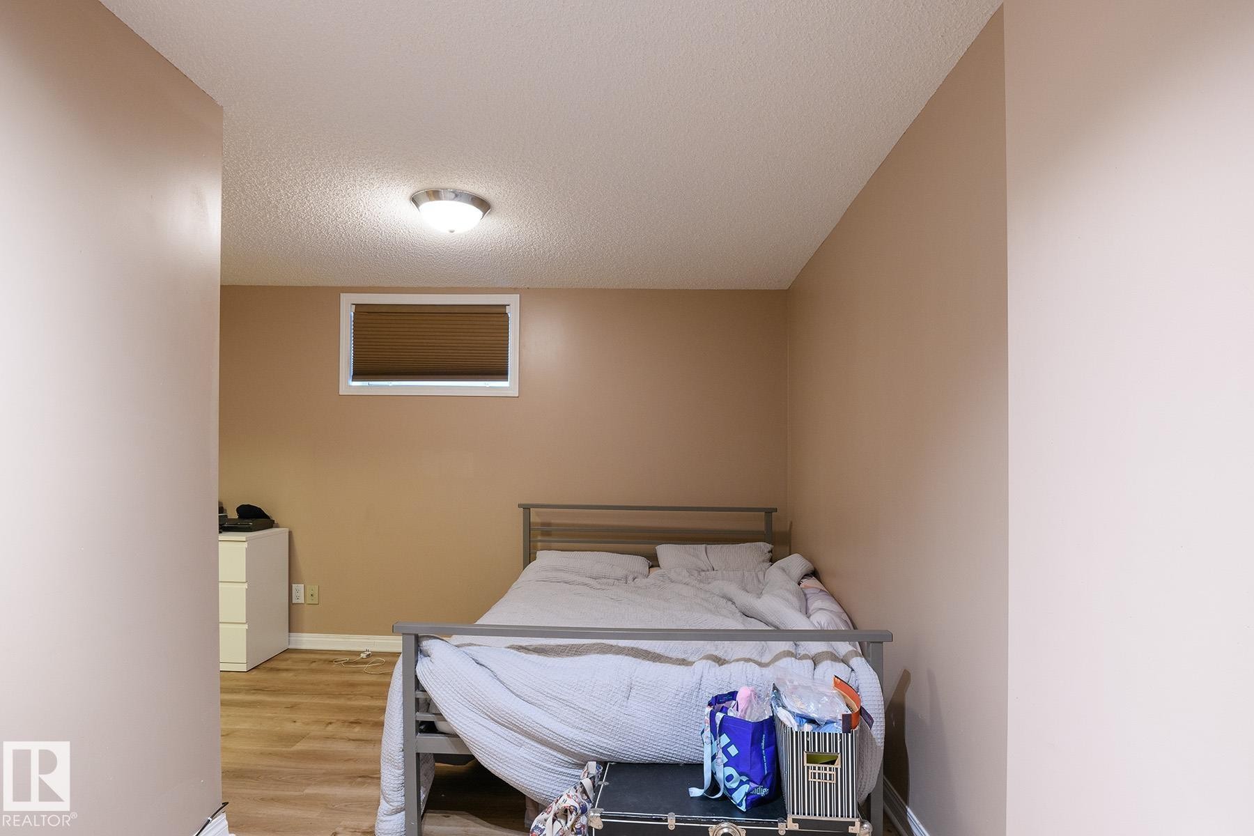 Room featuring wood-finish flooring, a neutral wall color, and a textured ceiling - 9607 75 Street, Edmonton, AB