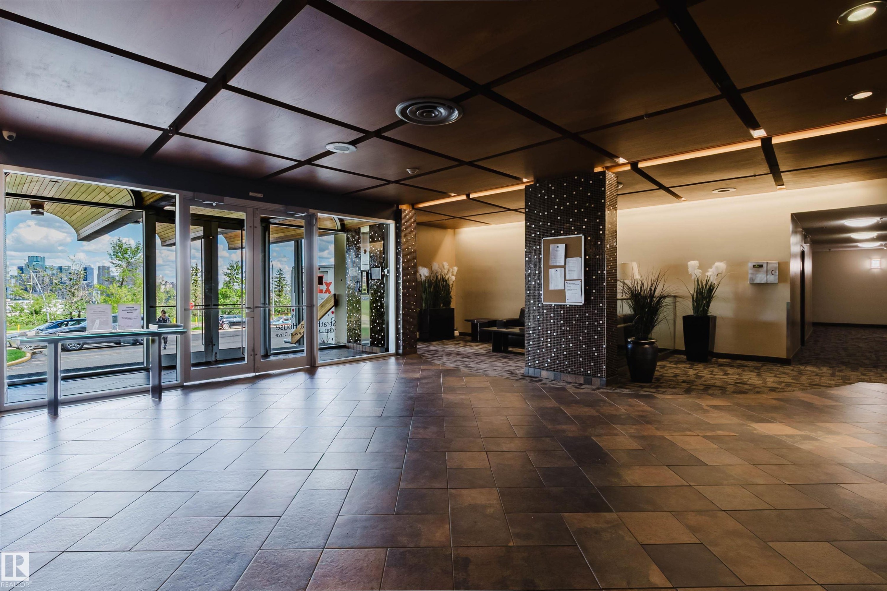 Spacious entry foyer featuring large format floor tiles, a coffered ceiling with integrated lighting, and a full glass storefront - 904 10883 Saskatchewan Drive, Edmonton, AB