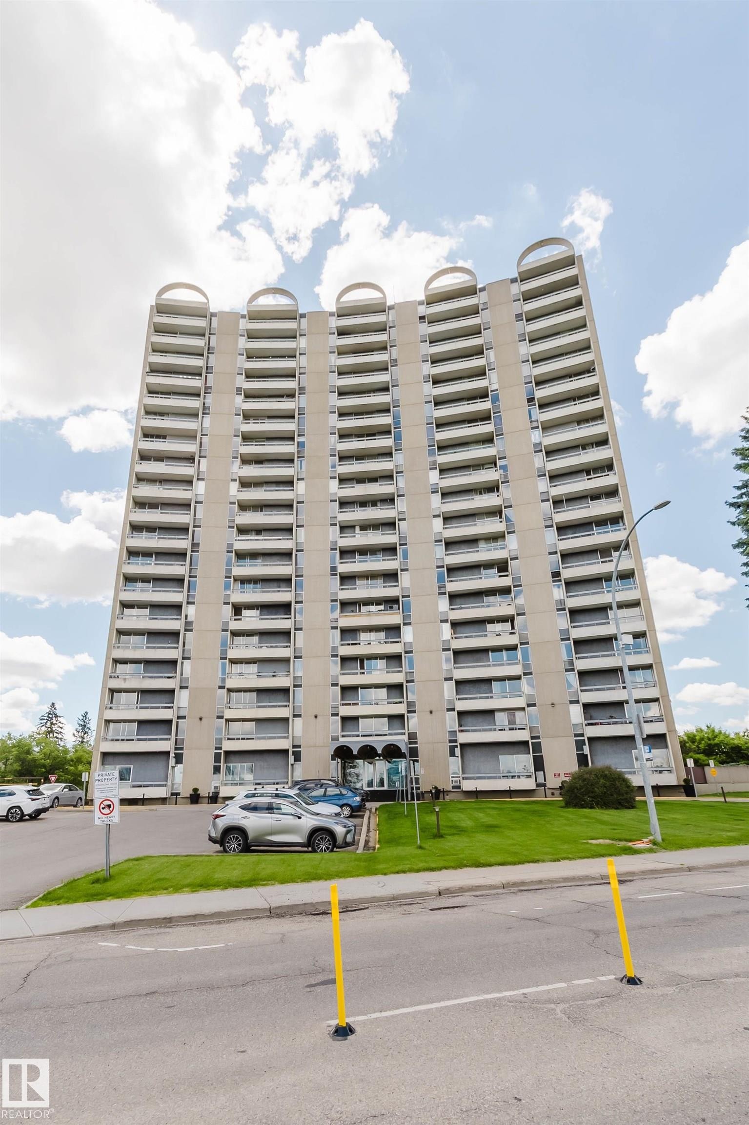 Multi-story residential building featuring a concrete facade with multiple balconies and a distinctive curved architectural element at the roofline - 904 10883 Saskatchewan Drive, Edmonton, AB