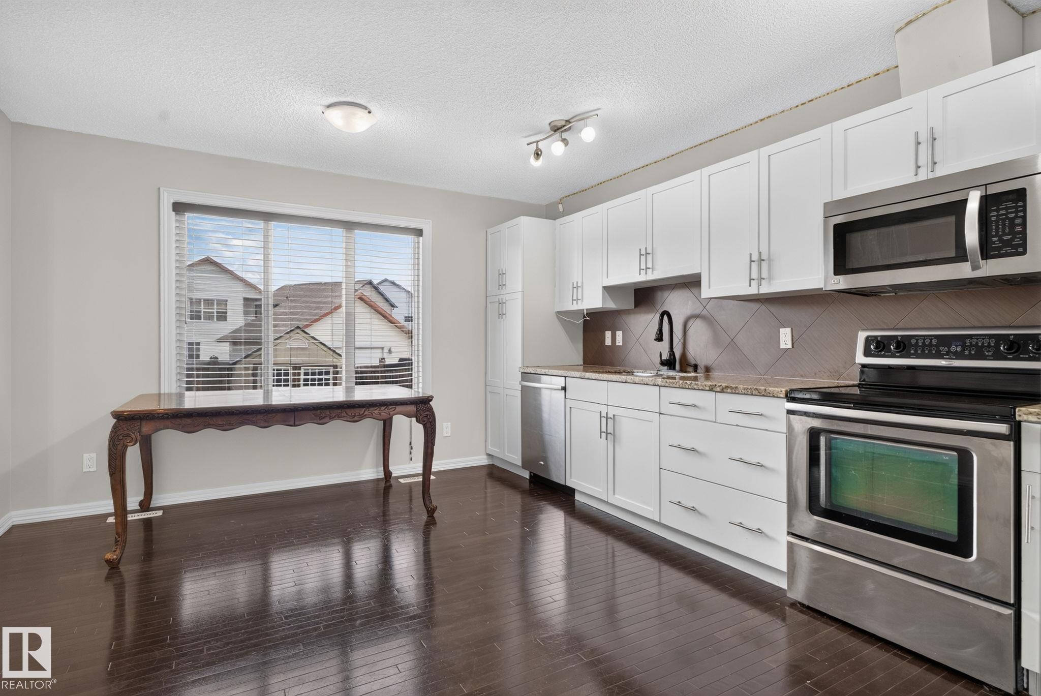 Kitchen featuring white cabinetry, stainless steel appliances, and wood-finish flooring - 545 Watt Boulevard Sw, Edmonton, AB - Indoor Photo Showing Kitchen With Stainless Steel Kitchen
