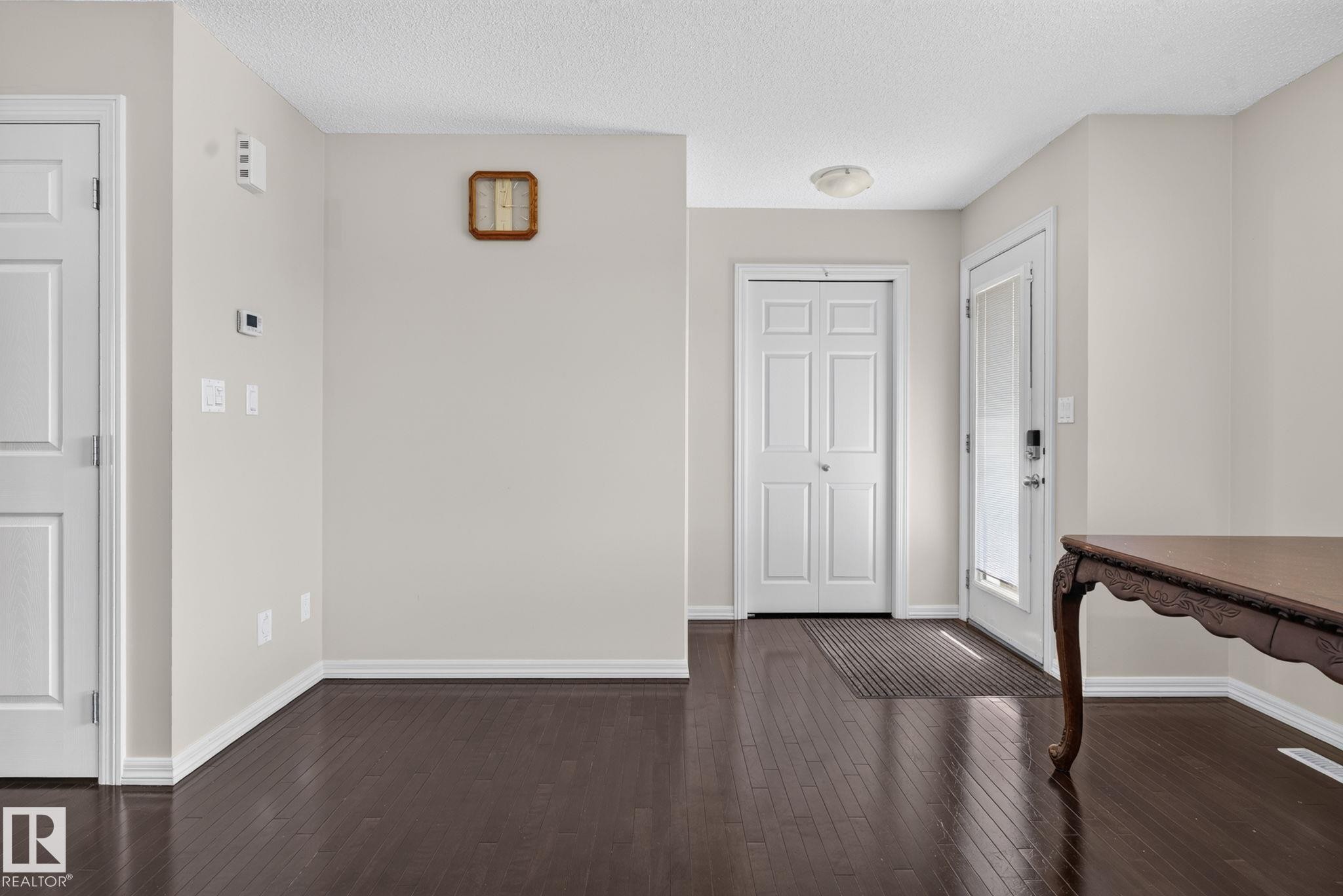 Entryway featuring rich wood-finish flooring, light neutral wall tones, white trim, and a white paneled front door with an integrated glass panel - 545 Watt Boulevard Sw, Edmonton, AB - Indoor Photo Showing Other Room