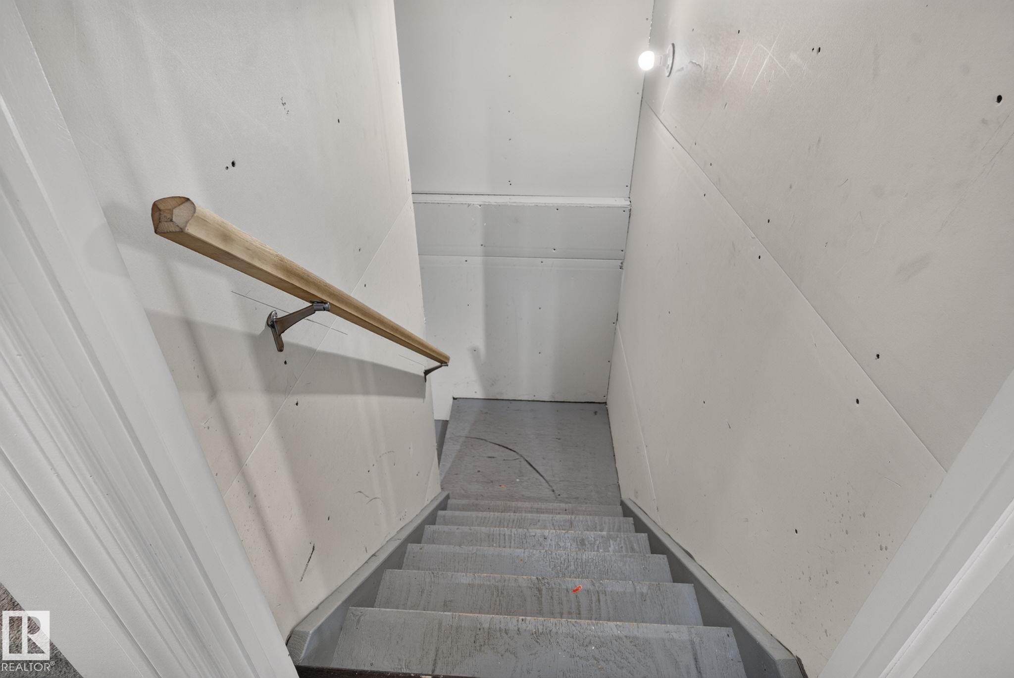 Staircase with a light wood handrail, white wall paneling, and a recessed ceiling light fixture - 545 Watt Boulevard Sw, Edmonton, AB - Indoor Photo Showing Other Room