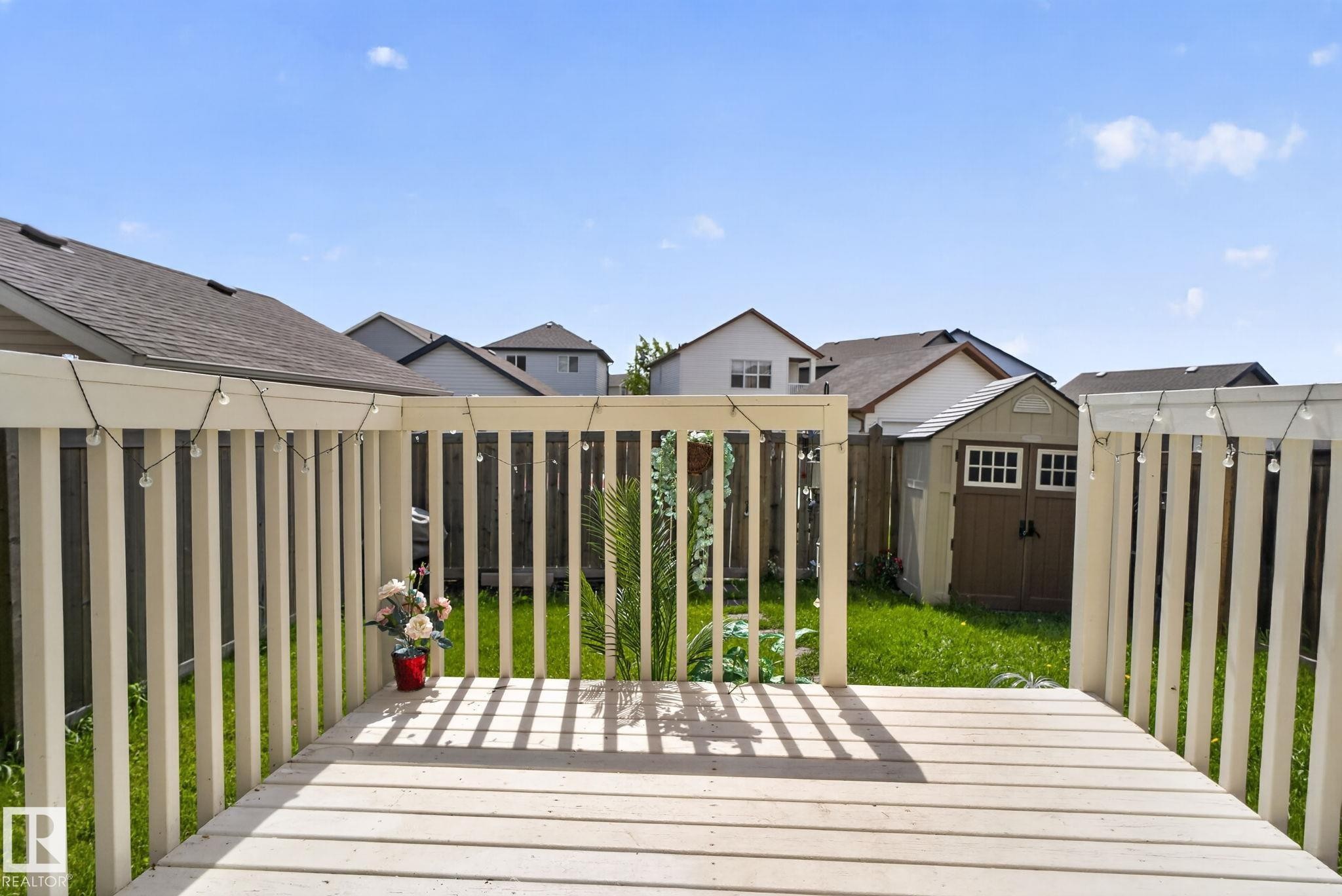 White-painted wood deck featuring a full railing and a storage shed in the backyard - 545 Watt Boulevard Sw, Edmonton, AB - Outdoor