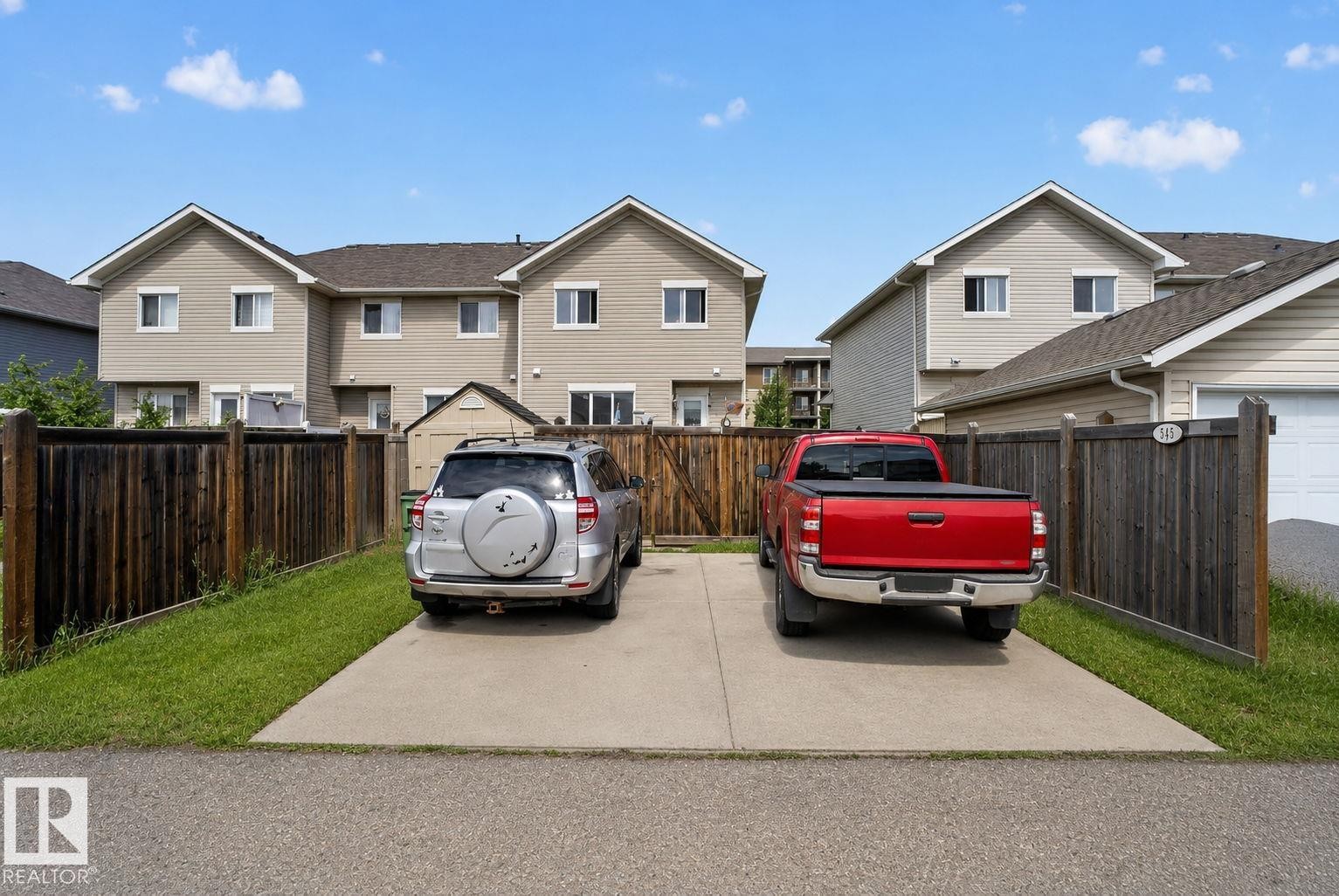 Concrete driveway providing off-street parking, bordered by wood fencing and a grass strip - 545 Watt Boulevard Sw, Edmonton, AB - Outdoor