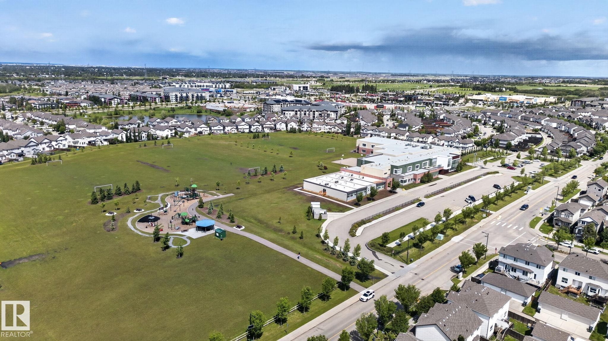 Expansive green space featuring a playground, sports fields, and paved walking paths - 545 Watt Boulevard Sw, Edmonton, AB - Outdoor With Body Of Water With View