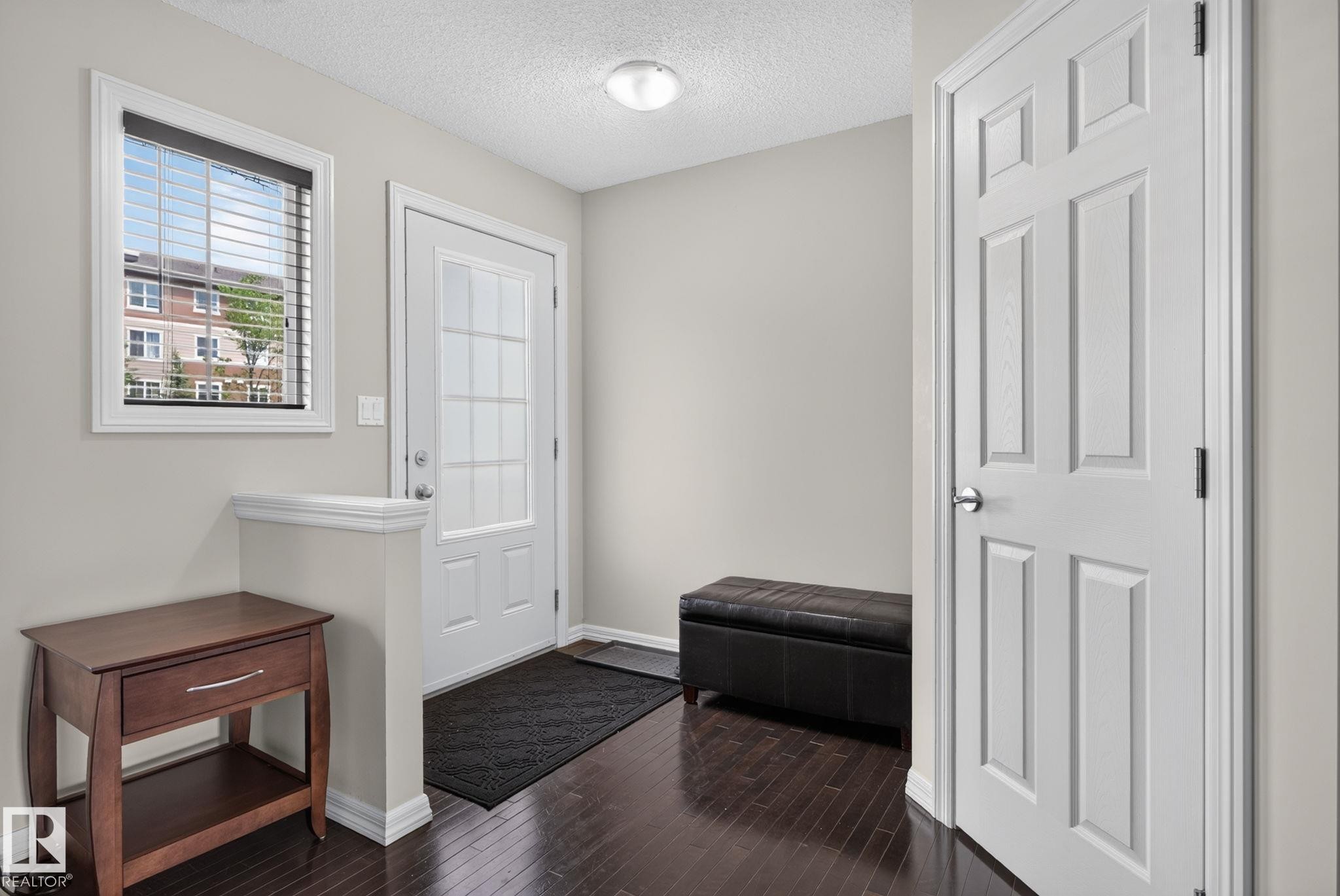 Entryway with dark wood-finish flooring, light neutral wall paint, and a bright white paneled door - 545 Watt Boulevard Sw, Edmonton, AB - Indoor Photo Showing Other Room
