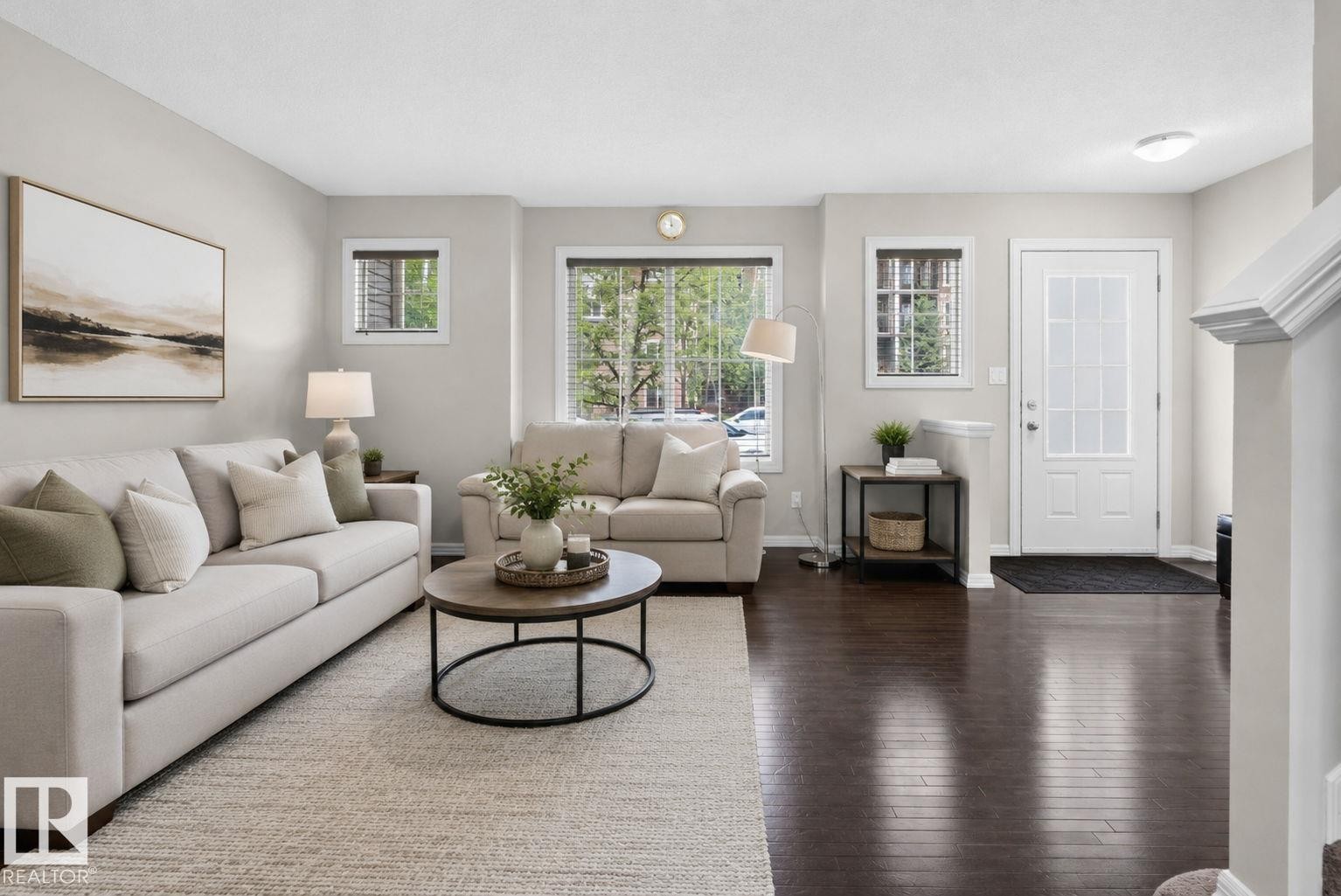 Living area featuring wood-finish flooring, light-colored walls, multiple windows with blinds, a white paneled entry door with frosted glass, and overhead lighting - 545 Watt Boulevard Sw, Edmonton, AB - Indoor Photo Showing Living Room