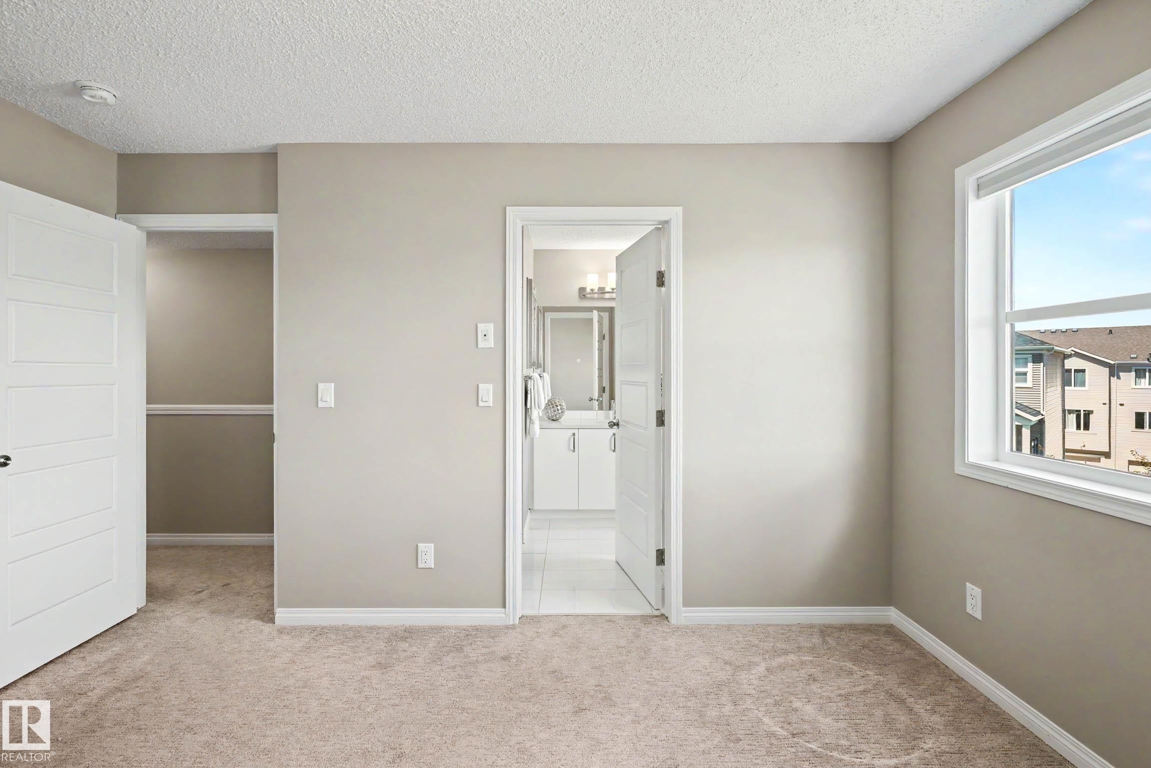 Neutral-toned bedroom featuring carpet flooring, a spacious open closet, and a white framed window - 53 2072 Wonnacott Way, Edmonton, AB