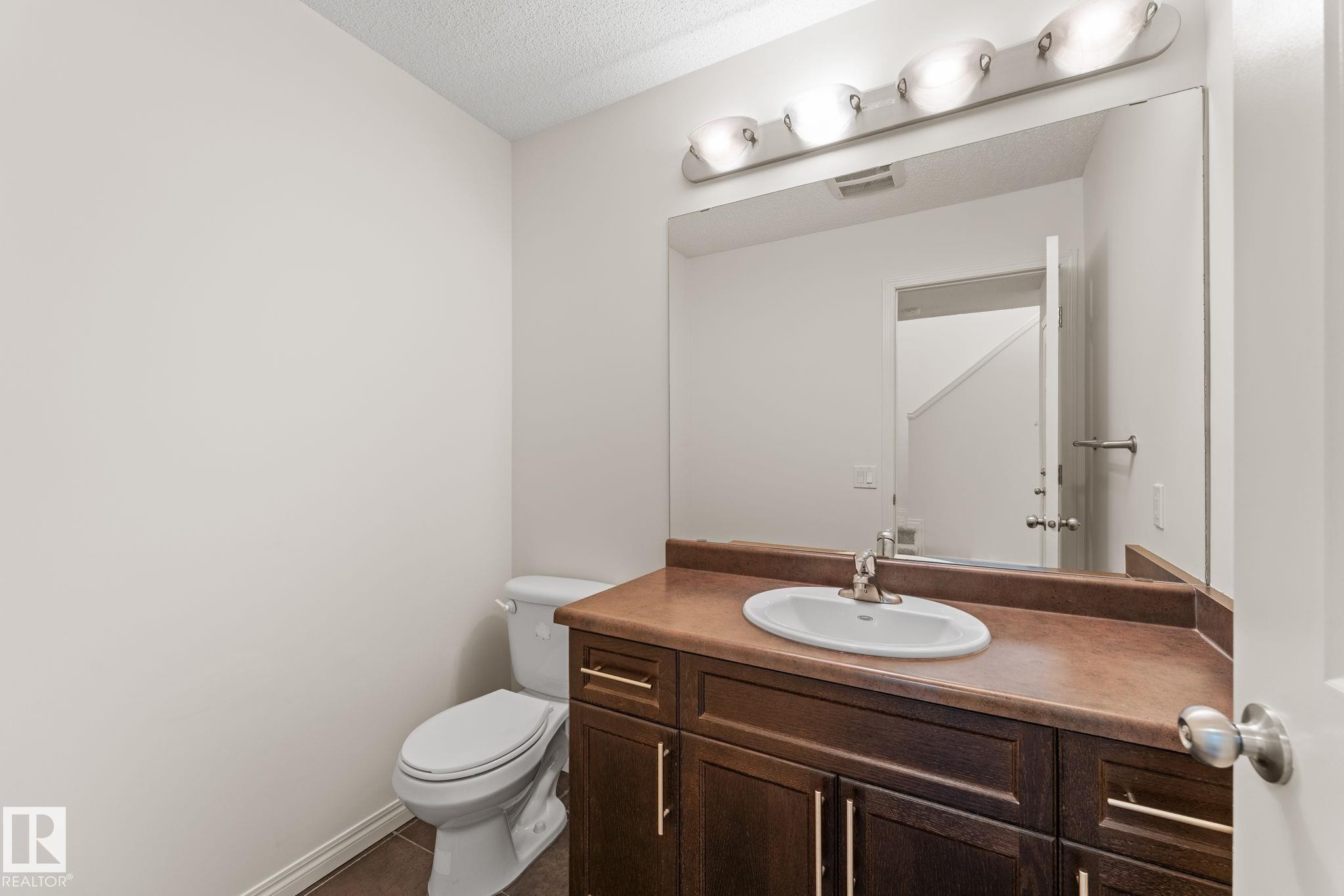 Bathroom vanity featuring a built-in sink, brown countertop, and dark wood-finish cabinetry with brushed nickel hardware - 12523 171 Avenue, Edmonton, AB