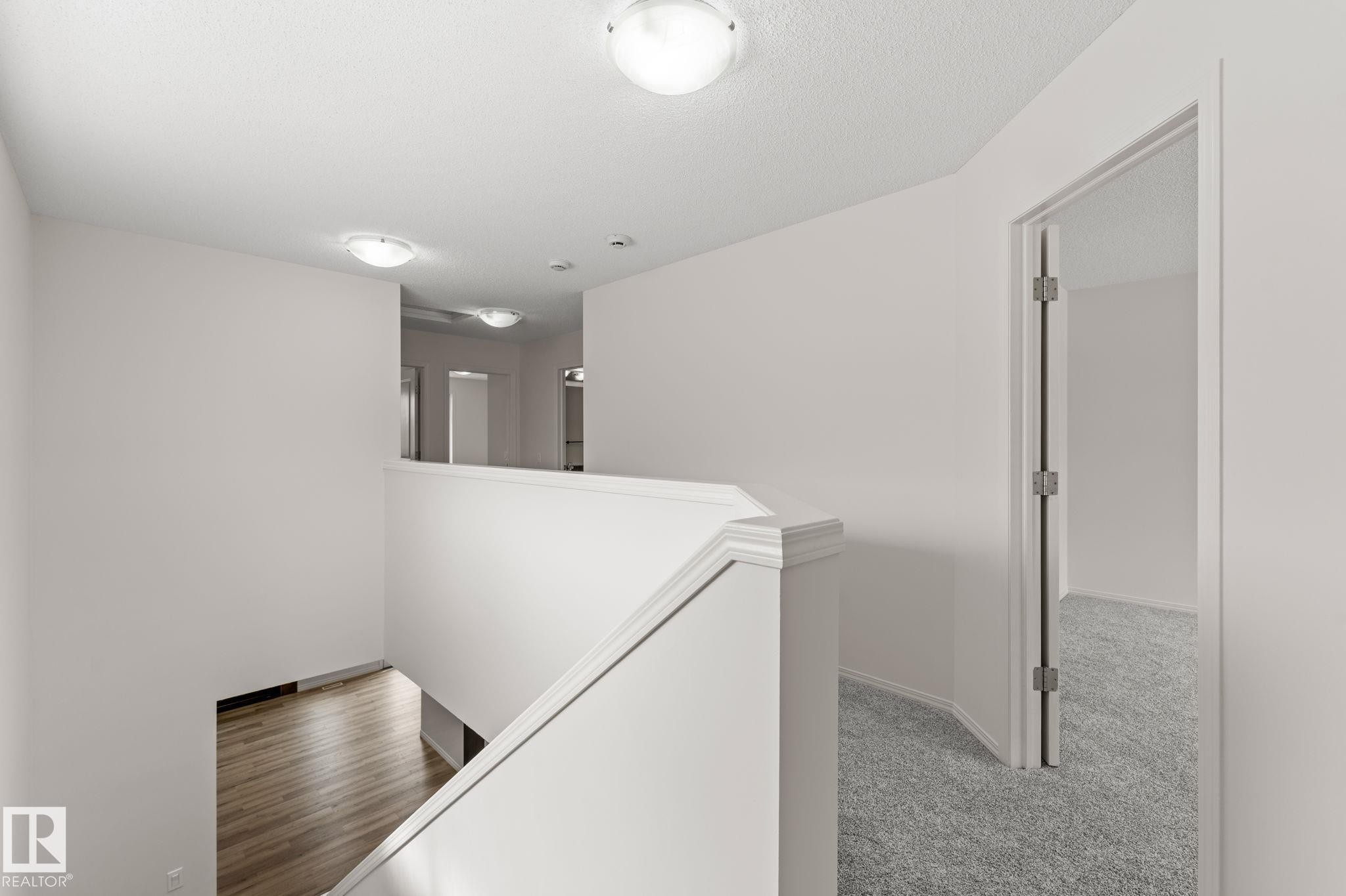 Upper-level landing featuring a white railing and neutral wall tones - 12523 171 Avenue, Edmonton, AB
