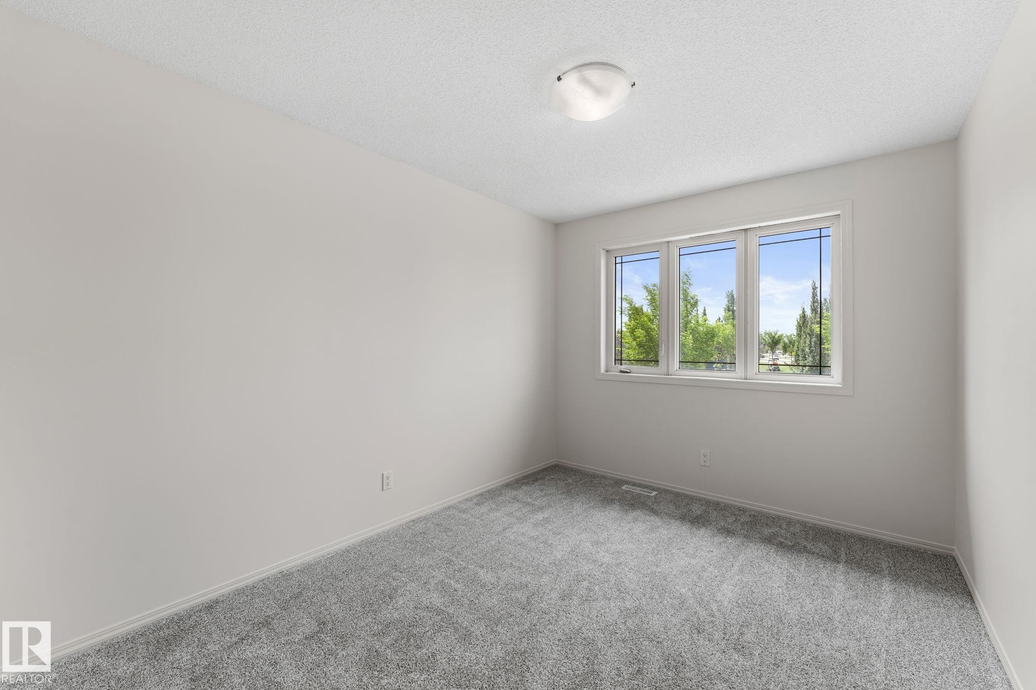 Bright room featuring a three-panel window, light-toned carpeting, and a ceiling-mounted flush light fixture - 12523 171 Avenue, Edmonton, AB