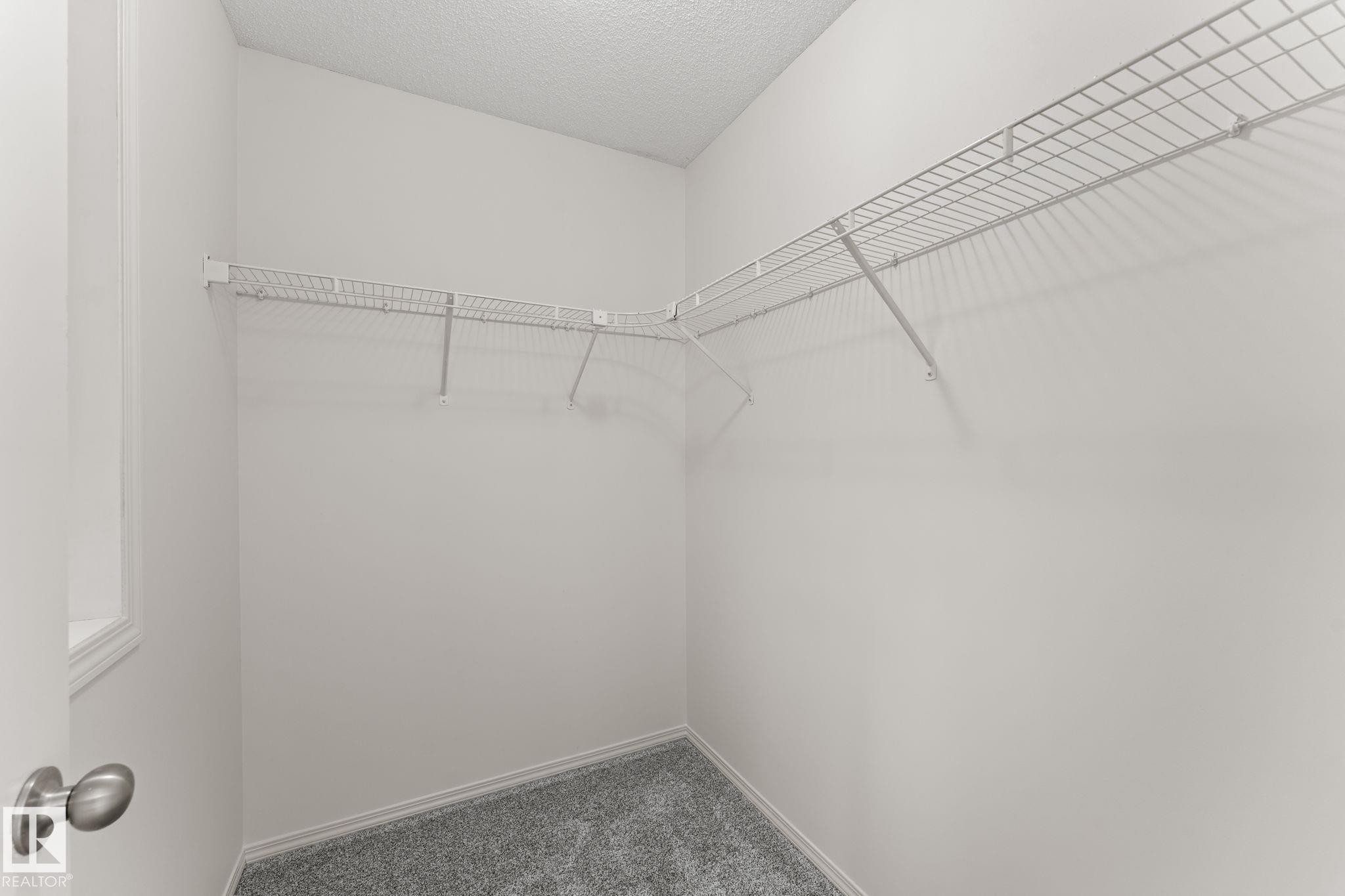 Walk-in closet featuring white wire shelving, gray textured carpeting, and a window for natural light - 12523 171 Avenue, Edmonton, AB