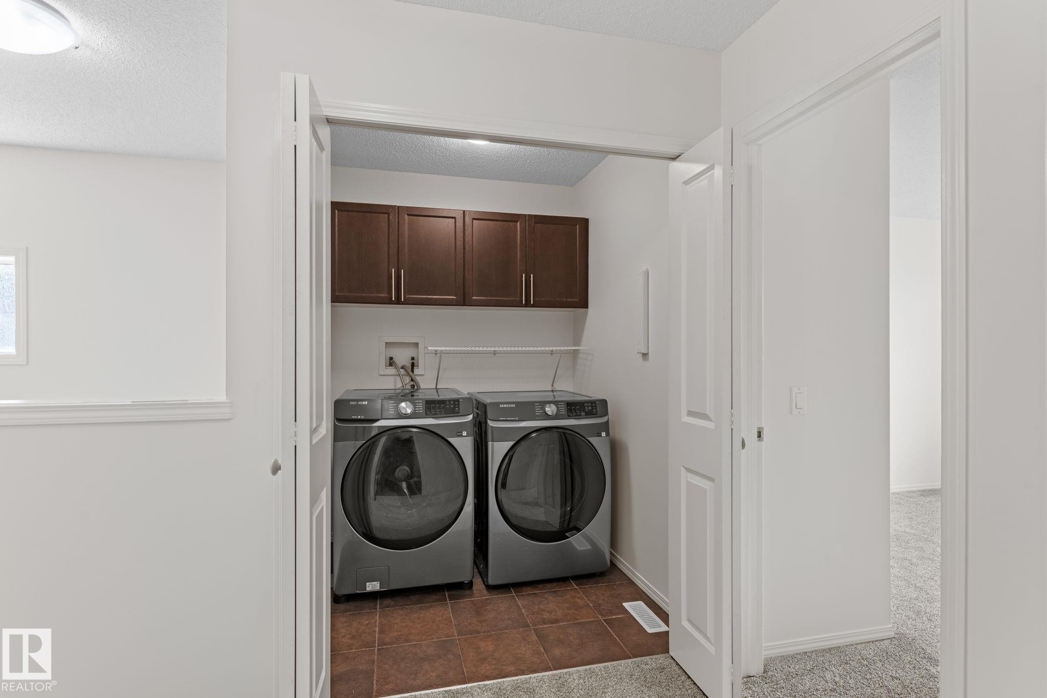 Dedicated laundry closet featuring a tile floor, built-in cabinetry, and a full-size washer and dryer - 12523 171 Avenue, Edmonton, AB