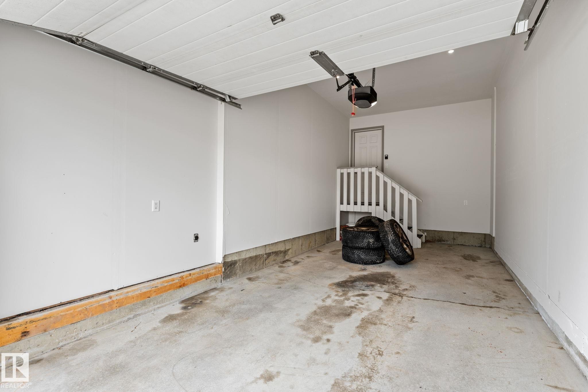 Spacious garage featuring a concrete floor, painted walls, and an overhead garage door opener mechanism - 12523 171 Avenue, Edmonton, AB