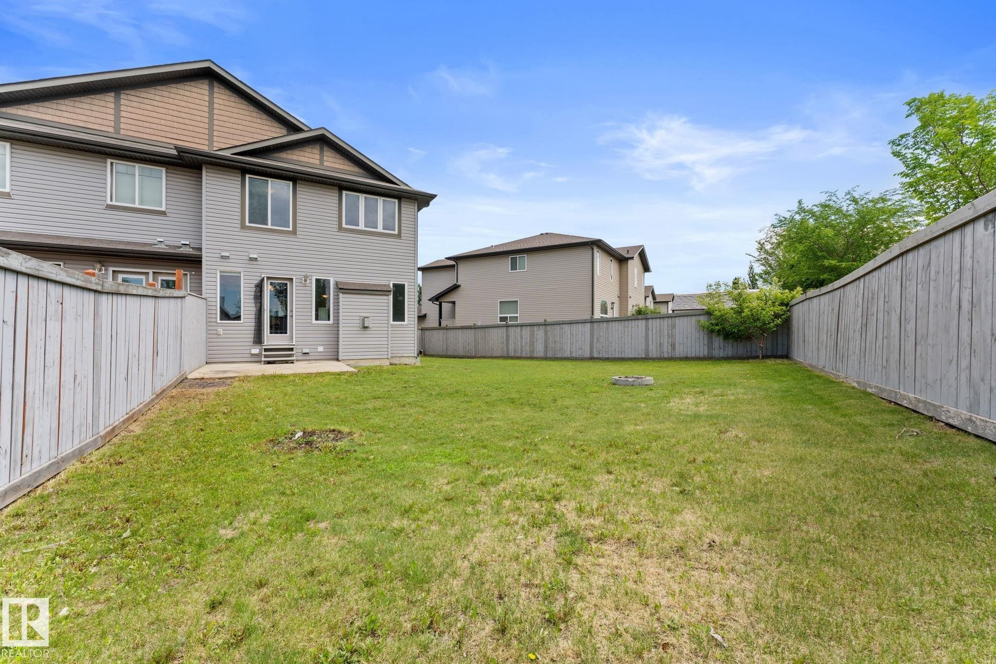 Spacious backyard featuring a manicured lawn, full fencing, and a concrete patio directly accessible from the dwelling - 12523 171 Avenue, Edmonton, AB
