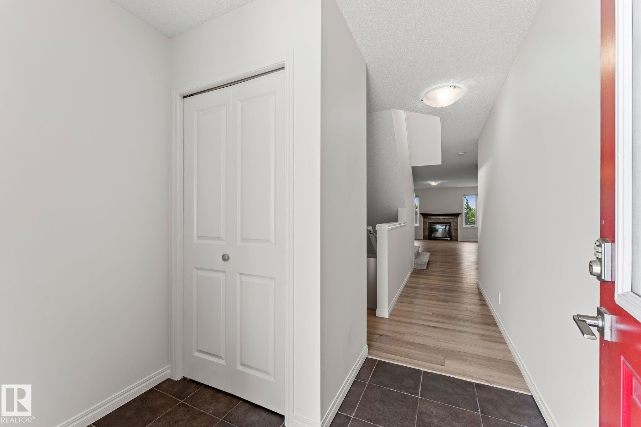Entryway featuring dark tile flooring, a red entry door, and a bi-fold closet - 12523 171 Avenue, Edmonton, AB
