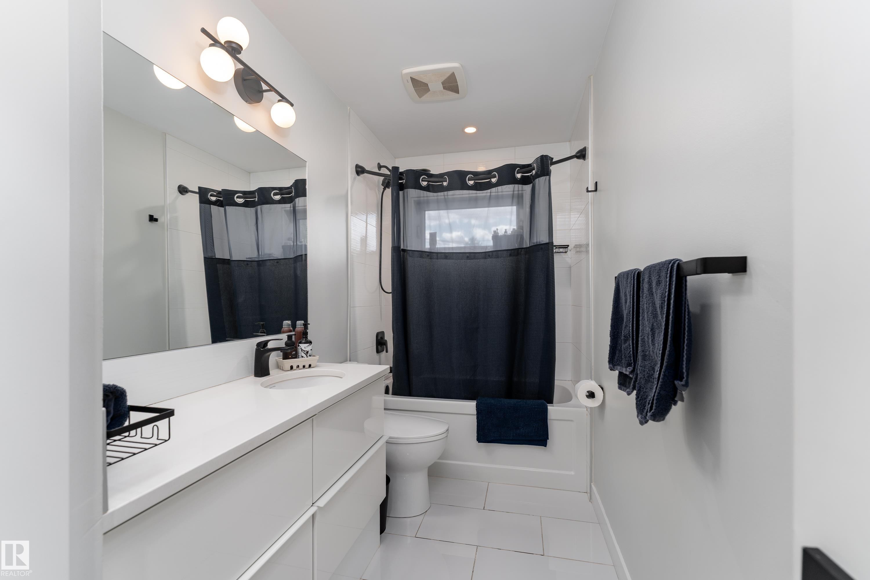 Contemporary bathroom featuring a spacious vanity with an integrated sink and matte black faucet - 10512 45 Street, Edmonton, AB