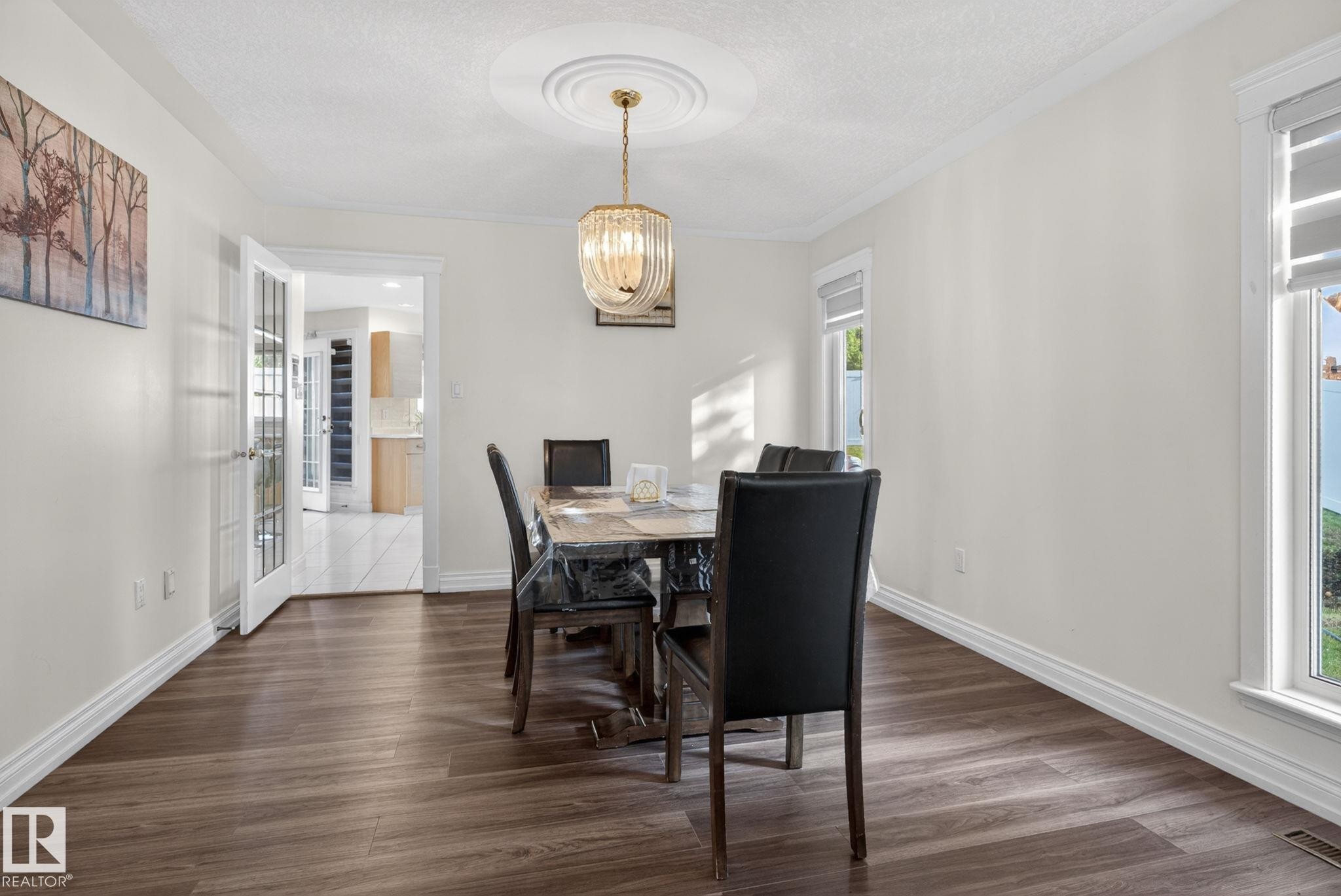 Spacious room with dark wood-finish flooring, white baseboards, and crown molding - 4615 43A Avenue, Edmonton, AB - Indoor Photo Showing Dining Room