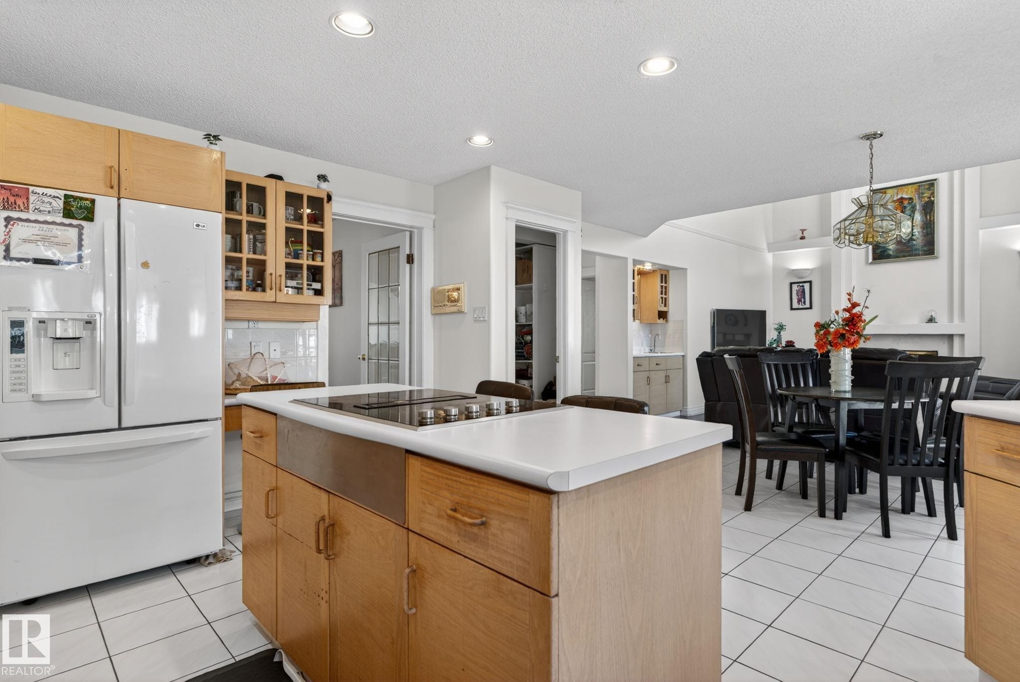 Kitchen island featuring a cooktop, white countertop, and natural wood cabinetry - 4615 43A Avenue, Edmonton, AB - Indoor Photo Showing Other Room
