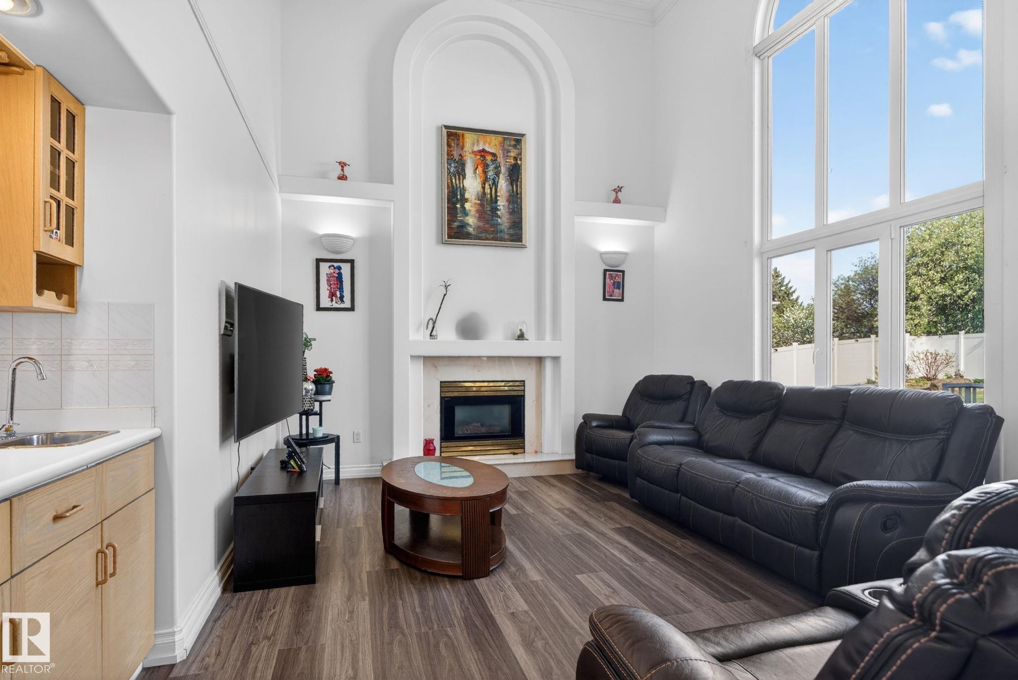 Spacious living area featuring high ceilings, tall arched windows, and wood-finish flooring - 4615 43A Avenue, Edmonton, AB - Indoor Photo Showing Living Room With Fireplace