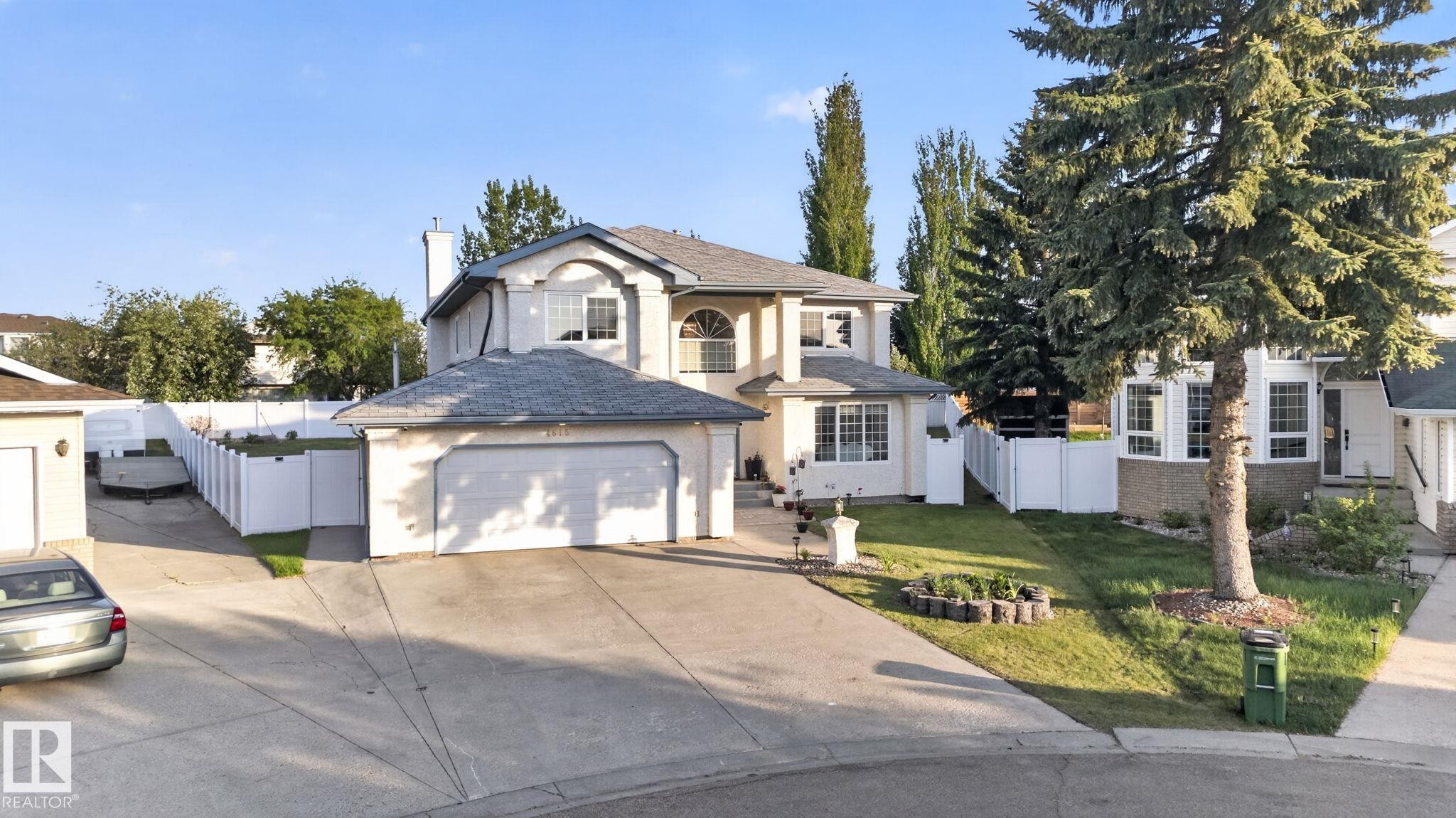 Stucco exterior residence with an attached double-door garage, concrete driveway, and a fenced yard - 4615 43A Avenue, Edmonton, AB - Outdoor