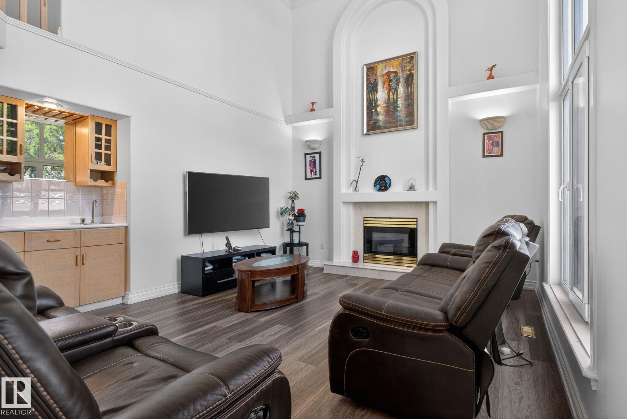 Spacious living area featuring high vaulted ceilings, wood-finish flooring, and a fireplace with a decorative mantel - 4615 43A Avenue, Edmonton, AB - Indoor Photo Showing Living Room With Fireplace