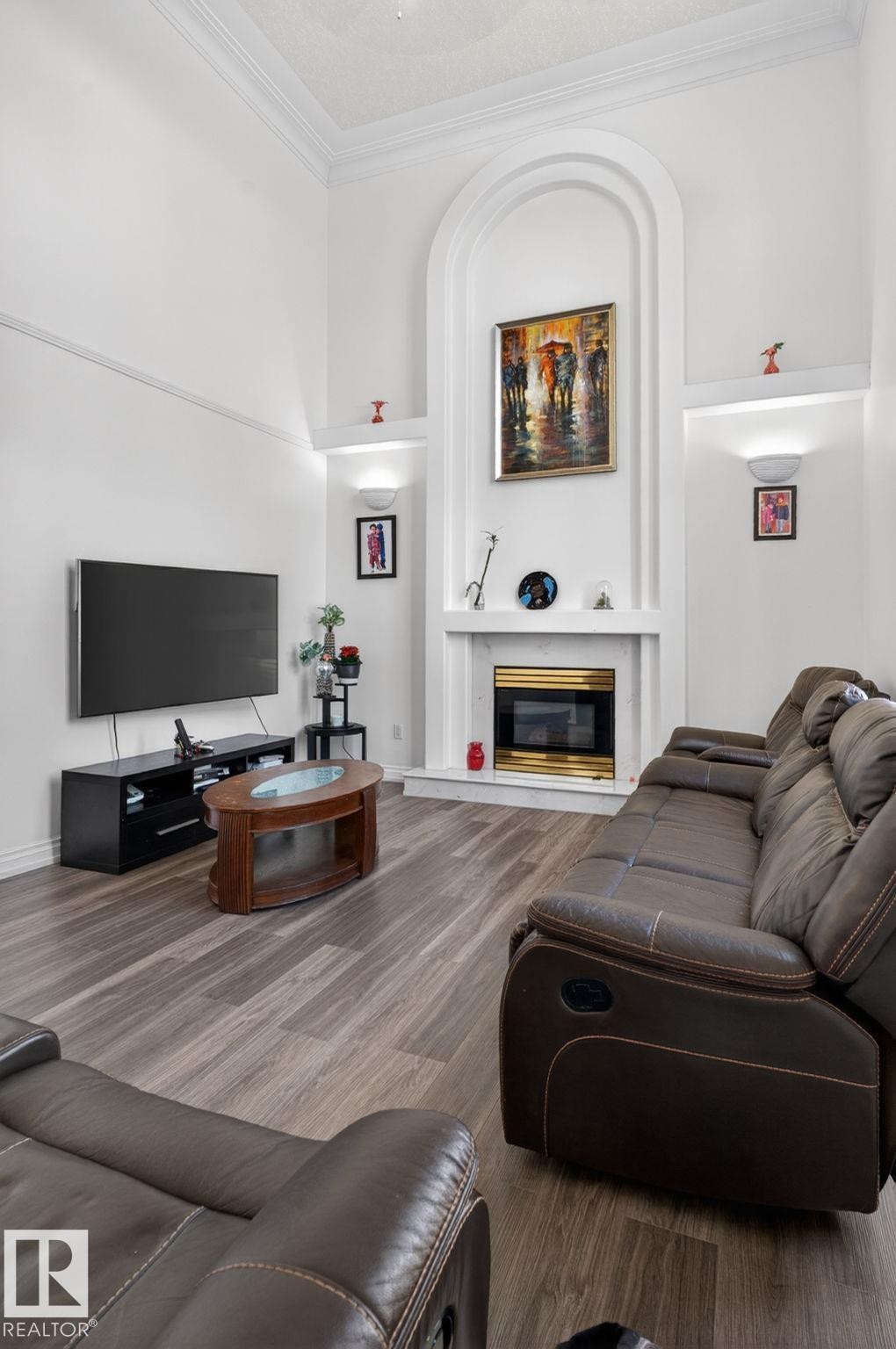 Living area featuring a floor-to-ceiling arched fireplace with an electric insert, integrated display niches with sconce lighting, and crown molding - 4615 43A Avenue, Edmonton, AB - Indoor With Fireplace