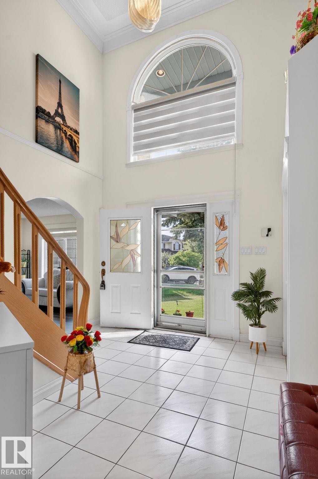 Grand foyer featuring a high ceiling, a decorative chandelier, and a large arched window with horizontal blinds - 4615 43A Avenue, Edmonton, AB - Indoor Photo Showing Other Room